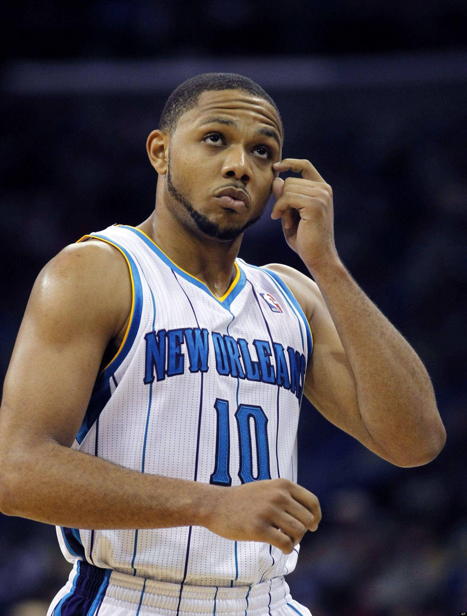 eric gordon 桌布 壁紙 — 一位專注的籃球運動員身穿紐奧良球衣，在明亮的場館燈光下調整耳機。