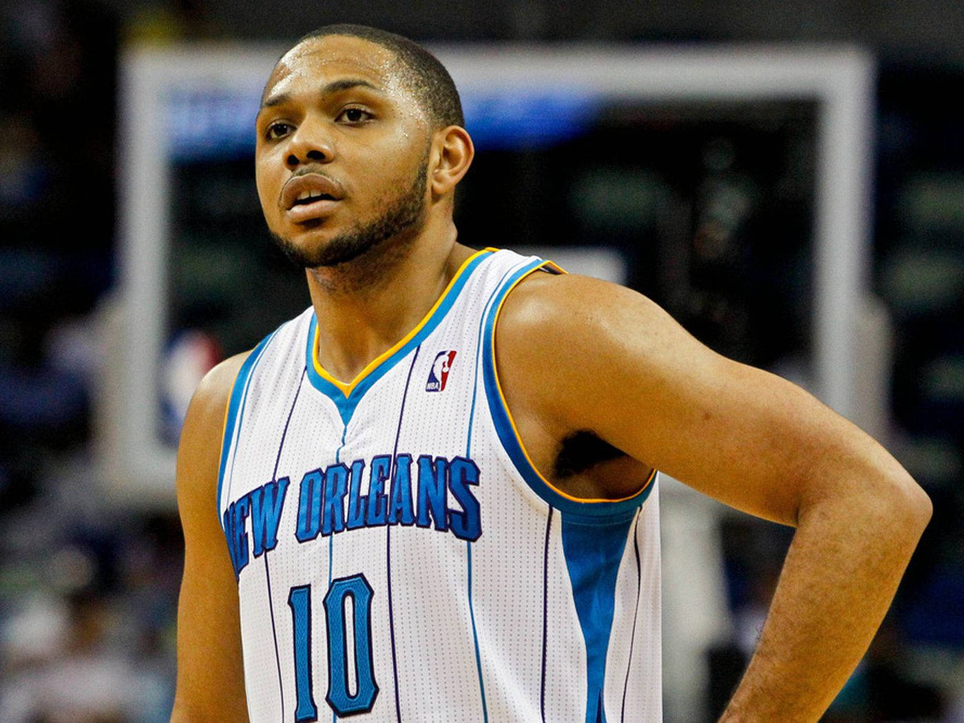 eric gordon 桌布 壁紙 — 一位專注的籃球運動員身穿紐奧良球衣，在明亮的場館燈光下進行室內比賽時雙手叉腰站立。