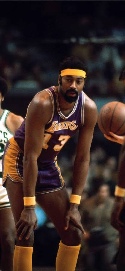 NBA 桌布 壁紙 — 一位專注的籃球運動員身穿紫金色湖人球衣，在場館燈光下蹲伏準備比賽。