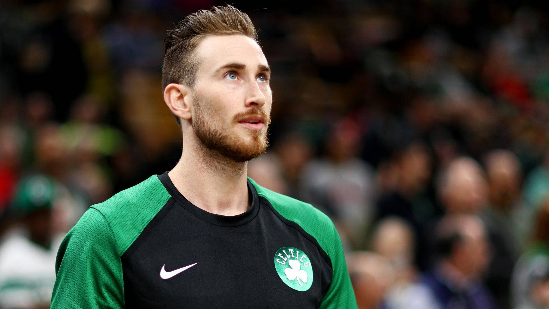gordon hayward 桌布 壁紙 — 一位專注的籃球運動員身穿綠色和黑色的塞爾提克球衣，在比賽中向上凝視，身後是模糊的人群。