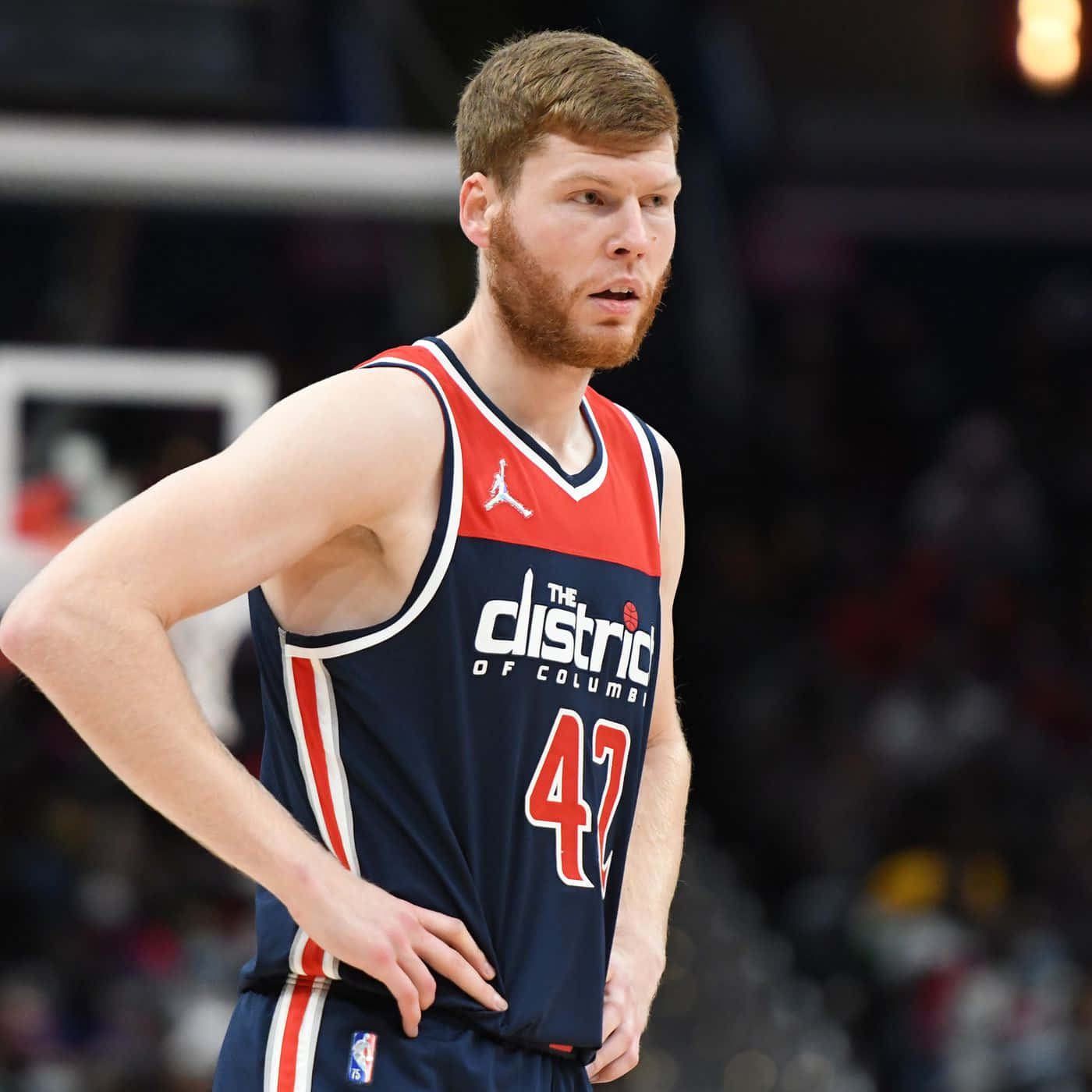 NBA 桌布 壁紙 — 一位專注的籃球運動員身穿華盛頓巫師隊球衣，在明亮的場館燈光下雙手叉腰站立於比賽中。