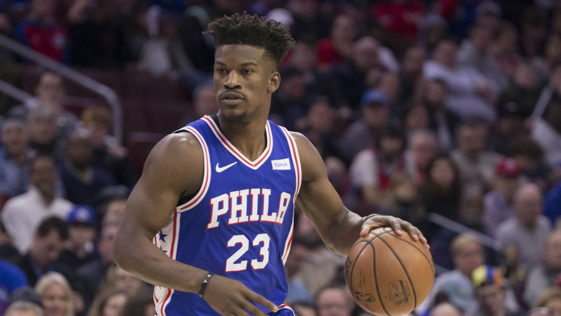 jimmy 桌布 壁紙 — 一位專注的籃球運動員身穿藍色Phila球衣，在明亮的場館燈光下於激烈比賽中運球。