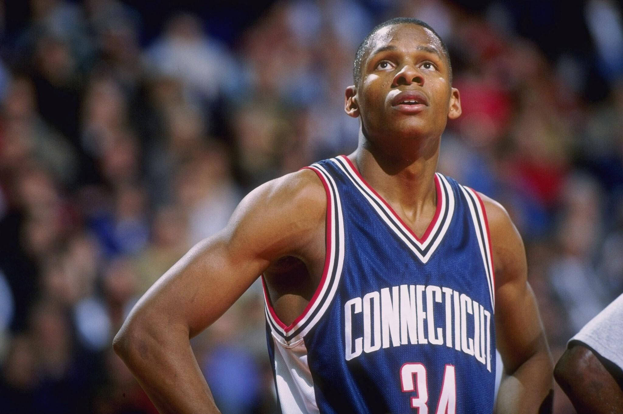 Ray Allen 桌布 壁紙 — 一位專注的籃球運動員身穿藍色康乃狄克州球衣，號碼34，站在球場上，身後是模糊的人群。
