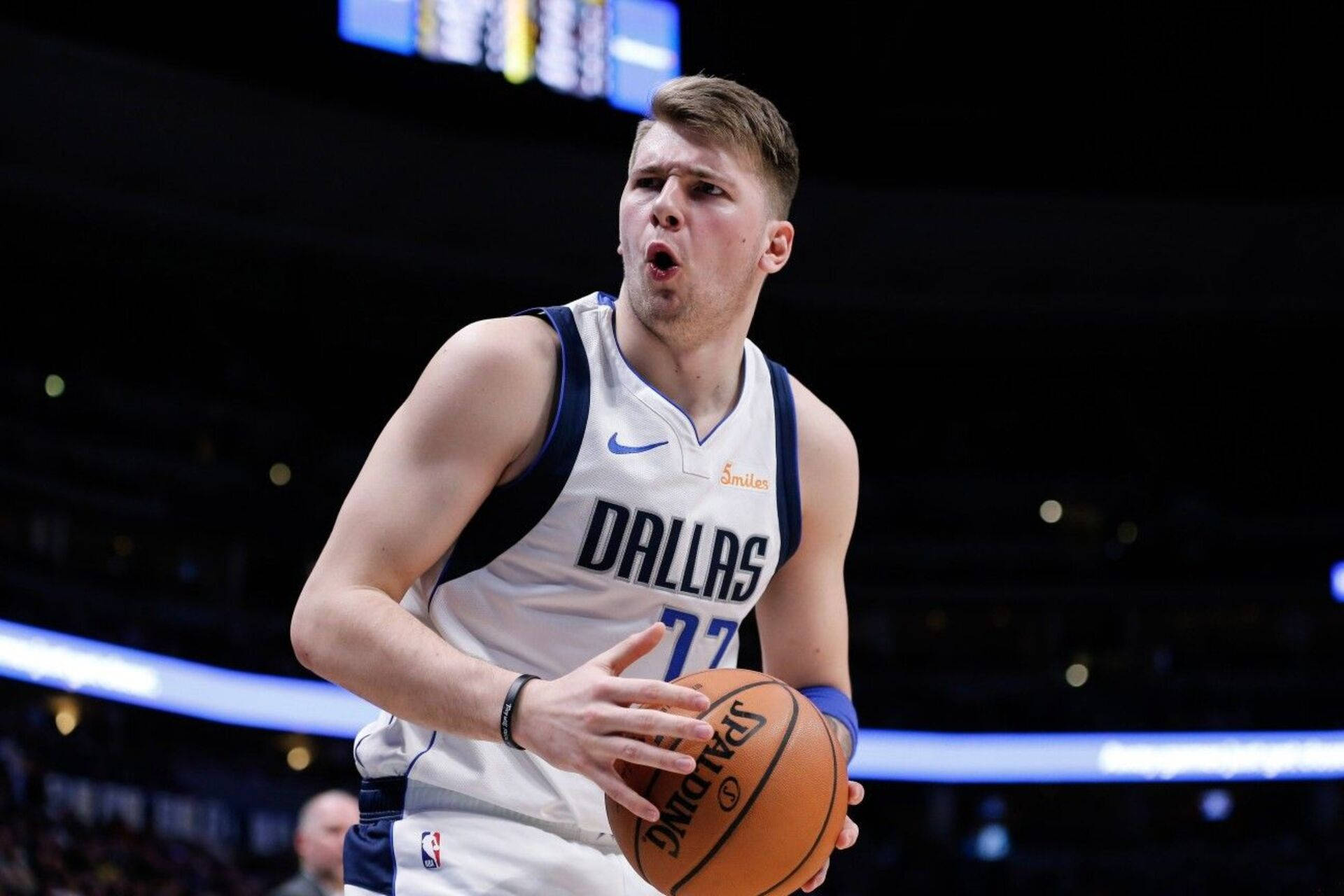 Luka 桌布 壁紙 — 一位專注的籃球運動員身穿達拉斯球衣，在球場燈光下激烈運球，背景有模糊的觀眾。