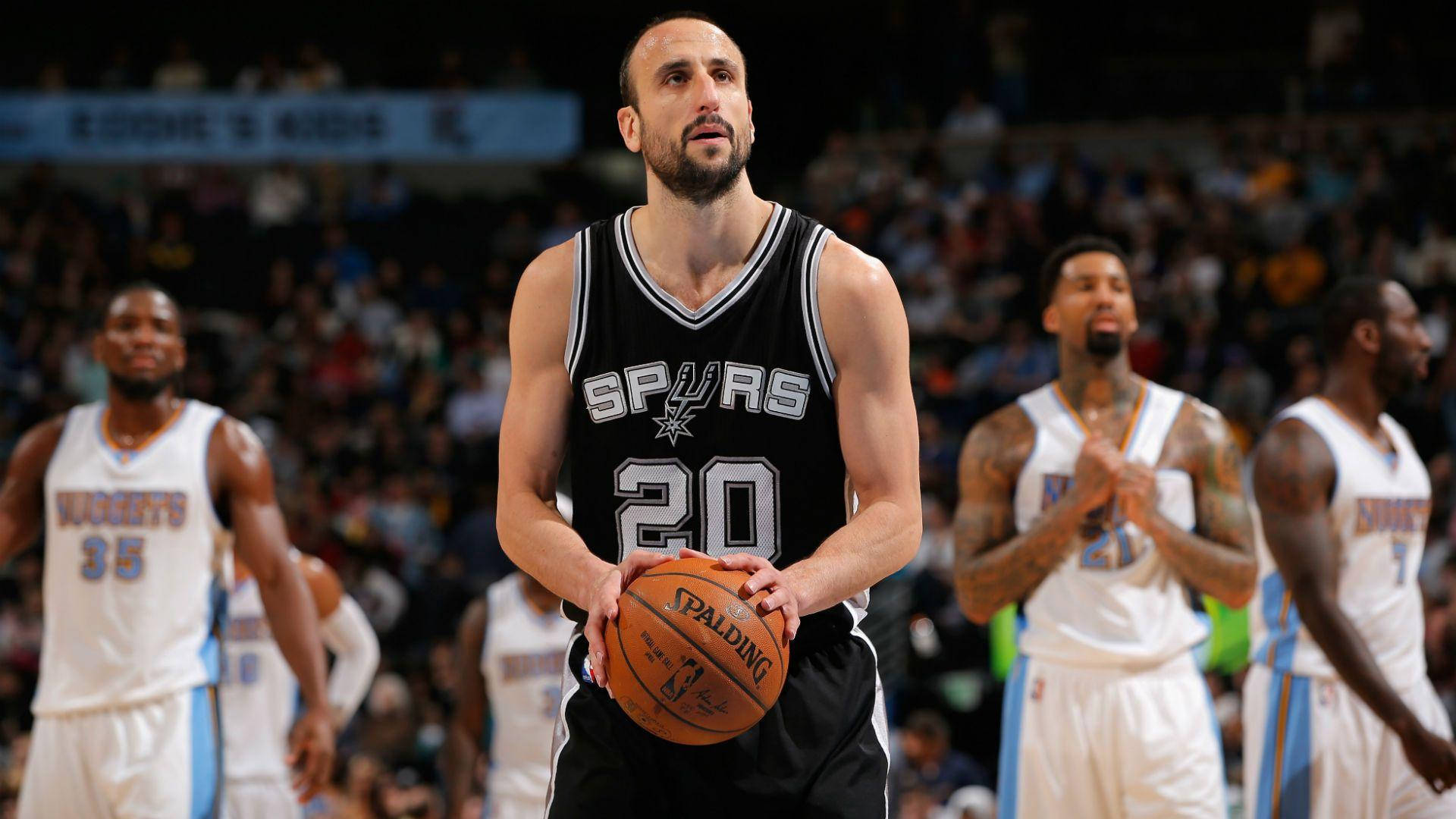 Manu 桌布 壁紙 — 一位專注的籃球運動員身穿馬刺球衣，在比賽中手持Spalding籃球，背景有隊友和觀眾。