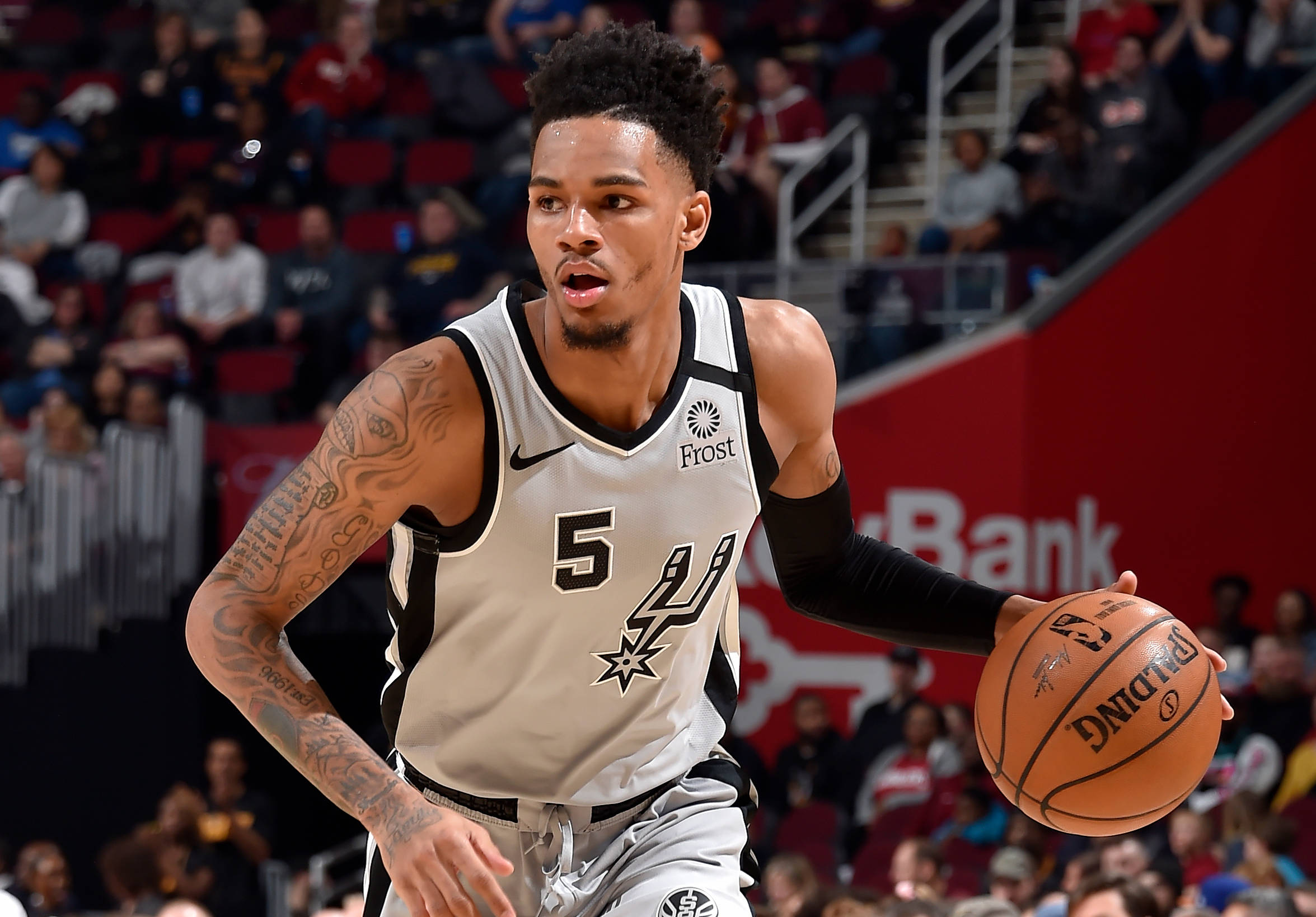 Dejounte Murray 桌布 壁紙 — 一位專注的籃球運動員身穿馬刺隊球衣，在場館燈光下於激烈比賽中運球。