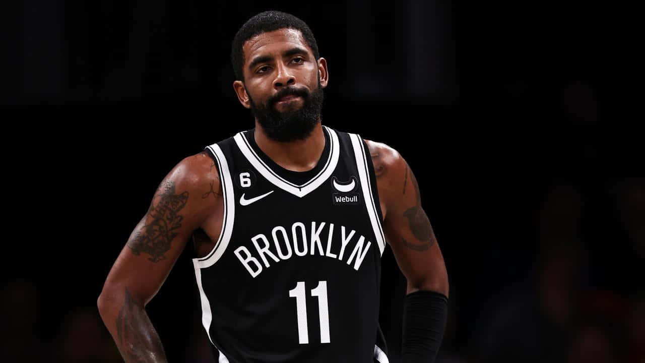Kyrie Irving Nets 桌布 壁紙 — 一位專注的籃球運動員身穿黑色布魯克林球衣，號碼11，站在深色背景前。