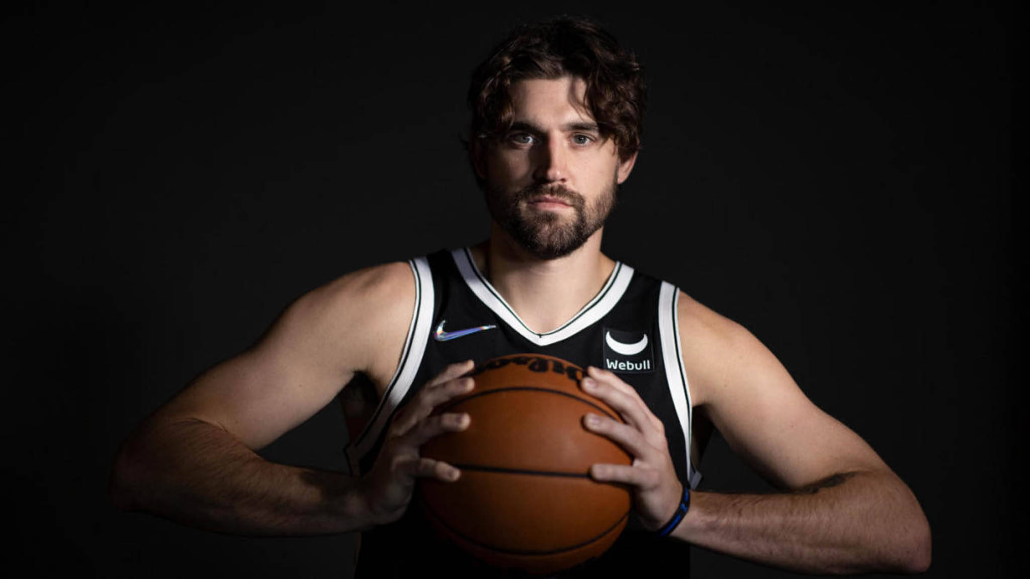 joe harris 桌布 壁紙 — 一位專注的籃球運動員身穿黑色球衣，在深色工作室背景前持球。