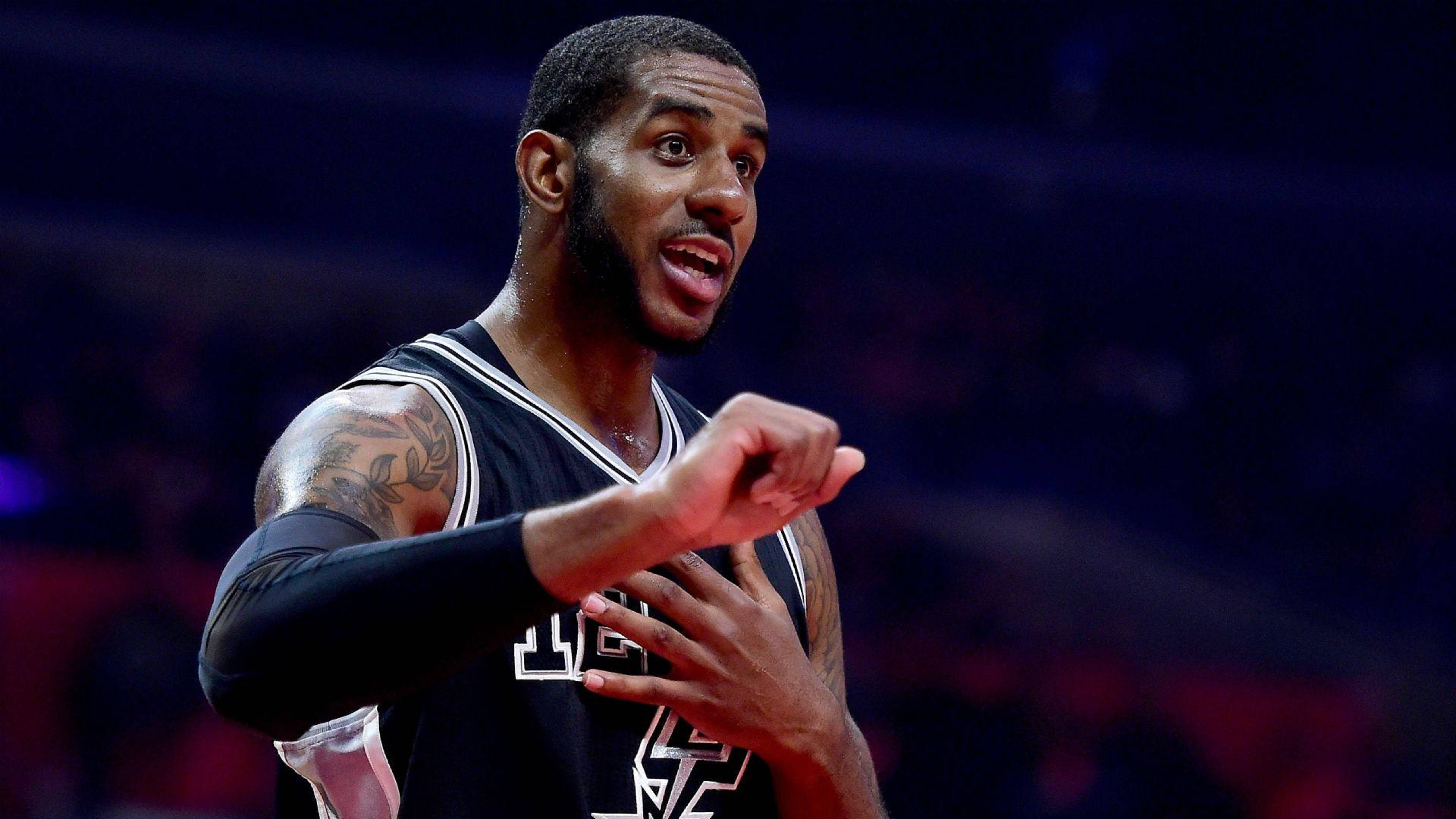 Lamarcus Aldridge 桌布 壁紙 — 一位專注的籃球運動員身穿黑色球衣，在明亮的場館燈光下比賽中激烈地做手勢。