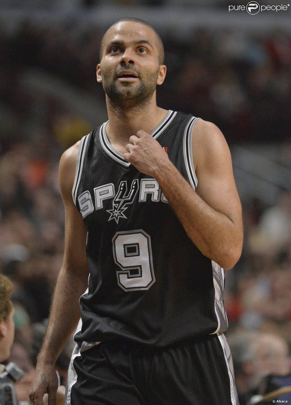 Tony Parker 桌布 壁紙 — 一位專注的籃球運動員身穿黑色馬刺隊9號球衣，在明亮的場館燈光下於激烈的比賽中做手勢。