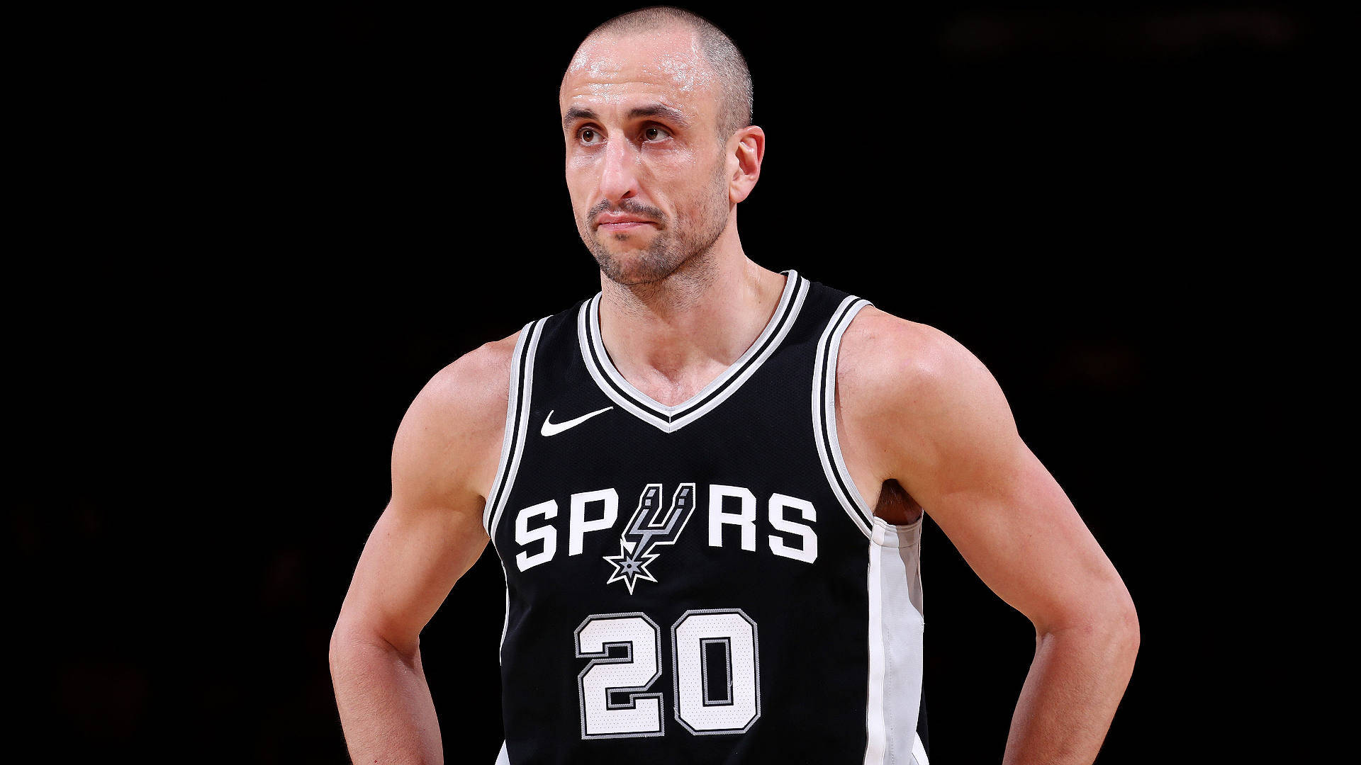 Manu 桌布 壁紙 — 一位專注的籃球運動員身穿黑色馬刺隊20號球衣，站在深色背景前。