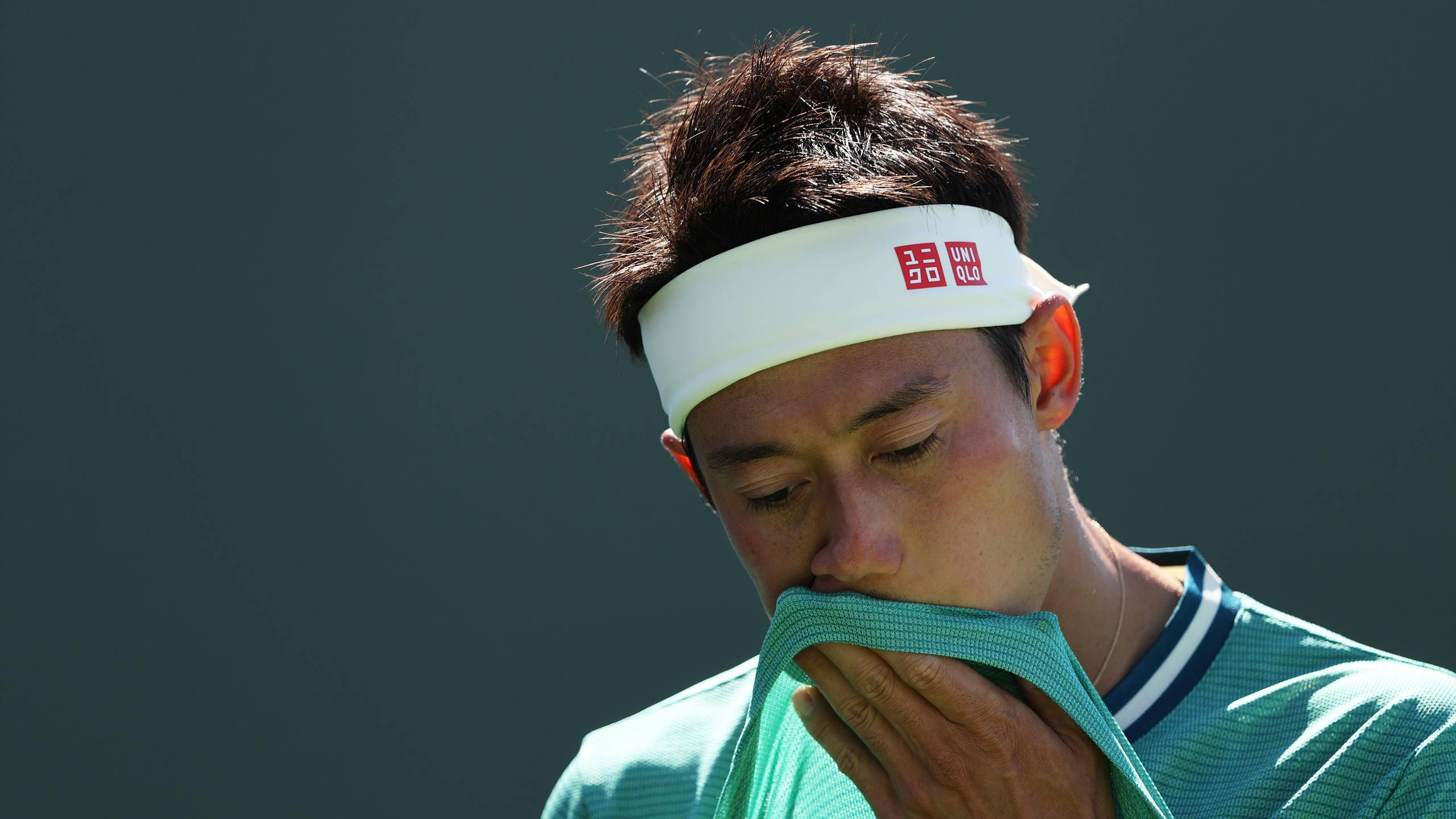 Athlete 桌布 壁紙 — 一位專注的網球運動員在明亮的陽光下用襯衫擦汗，背景為深色。