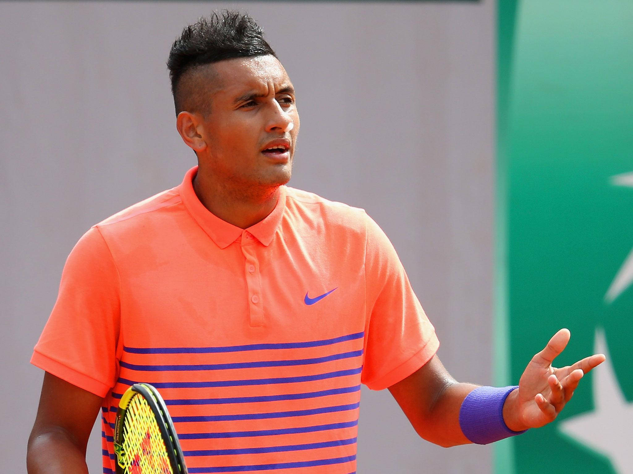 Kyrgios 桌布 壁紙 — 一位專注的網球選手穿著橙色條紋襯衫，在紅土比賽中用球拍做手勢。