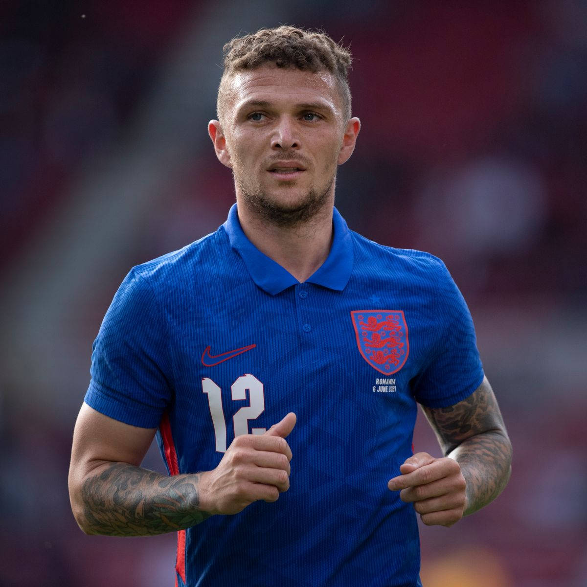 England Football 桌布 壁紙 — 一位專注的英格蘭足球員身穿藍色球衣，背號12，在比賽中豎起大拇指。