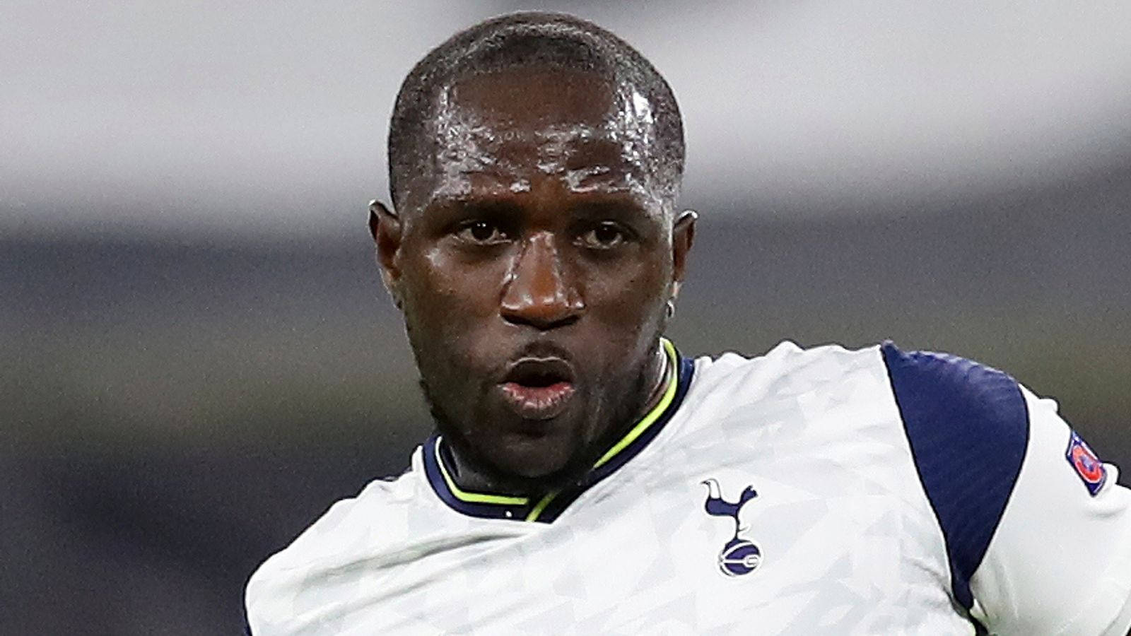 Football Players 桌布 壁紙 — 一位專注的足球員身穿白色和藍色球衣，比賽時臉上汗水閃閃發光。