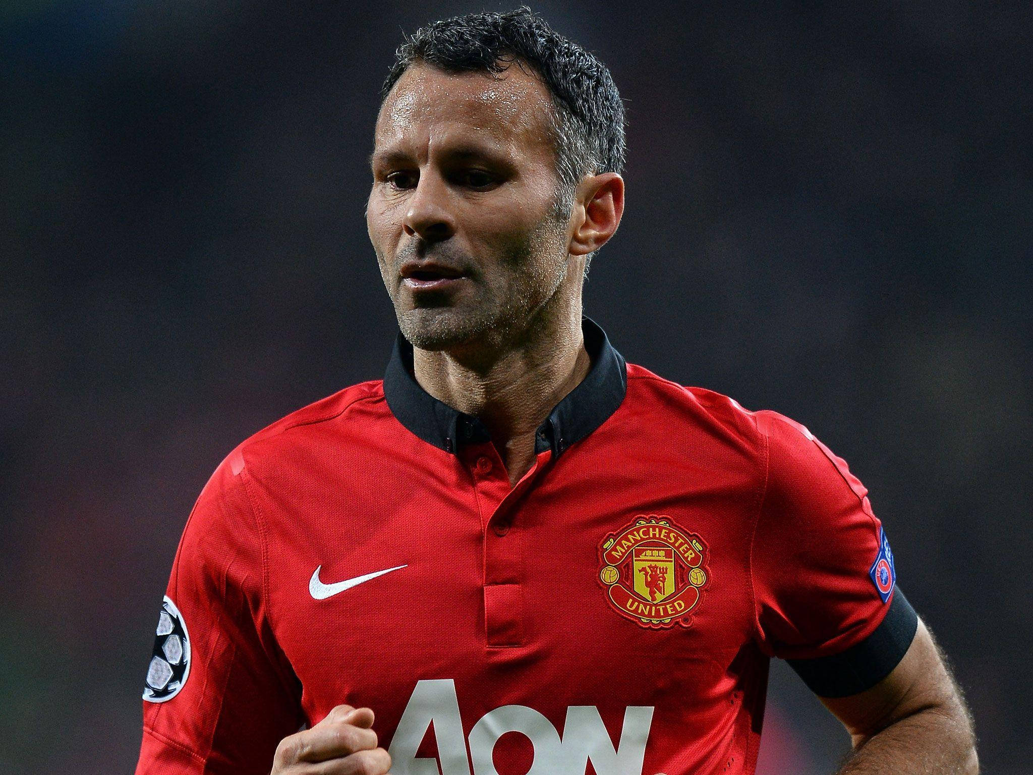 Ryan Giggs 桌布 壁紙 — 一位專注的足球員身穿紅色曼聯球衣，在夜間比賽中於球場燈光下奔跑。