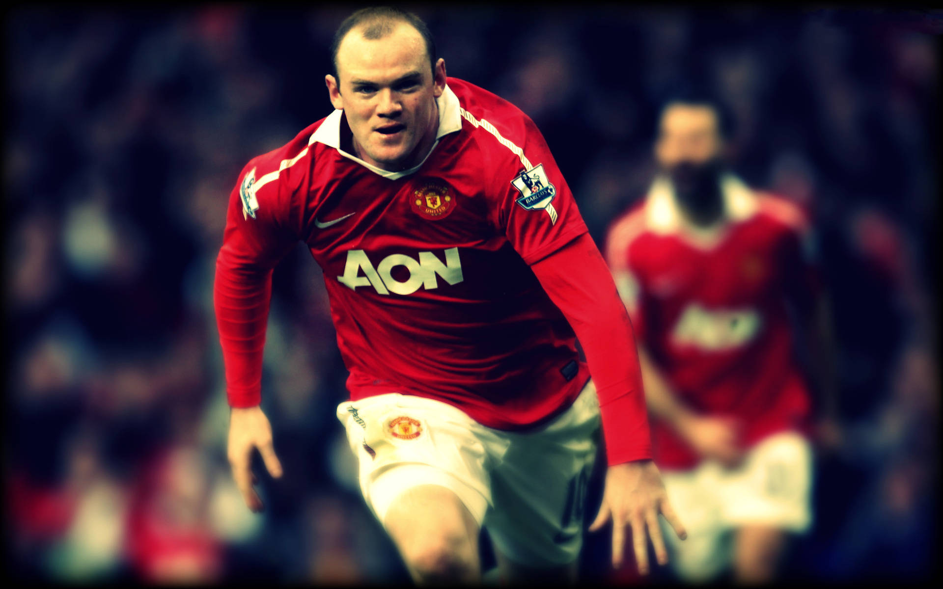 Rooney 桌布 壁紙 — 一位專注的足球員身穿紅色曼聯球衣，在比賽中堅定地向前衝刺。