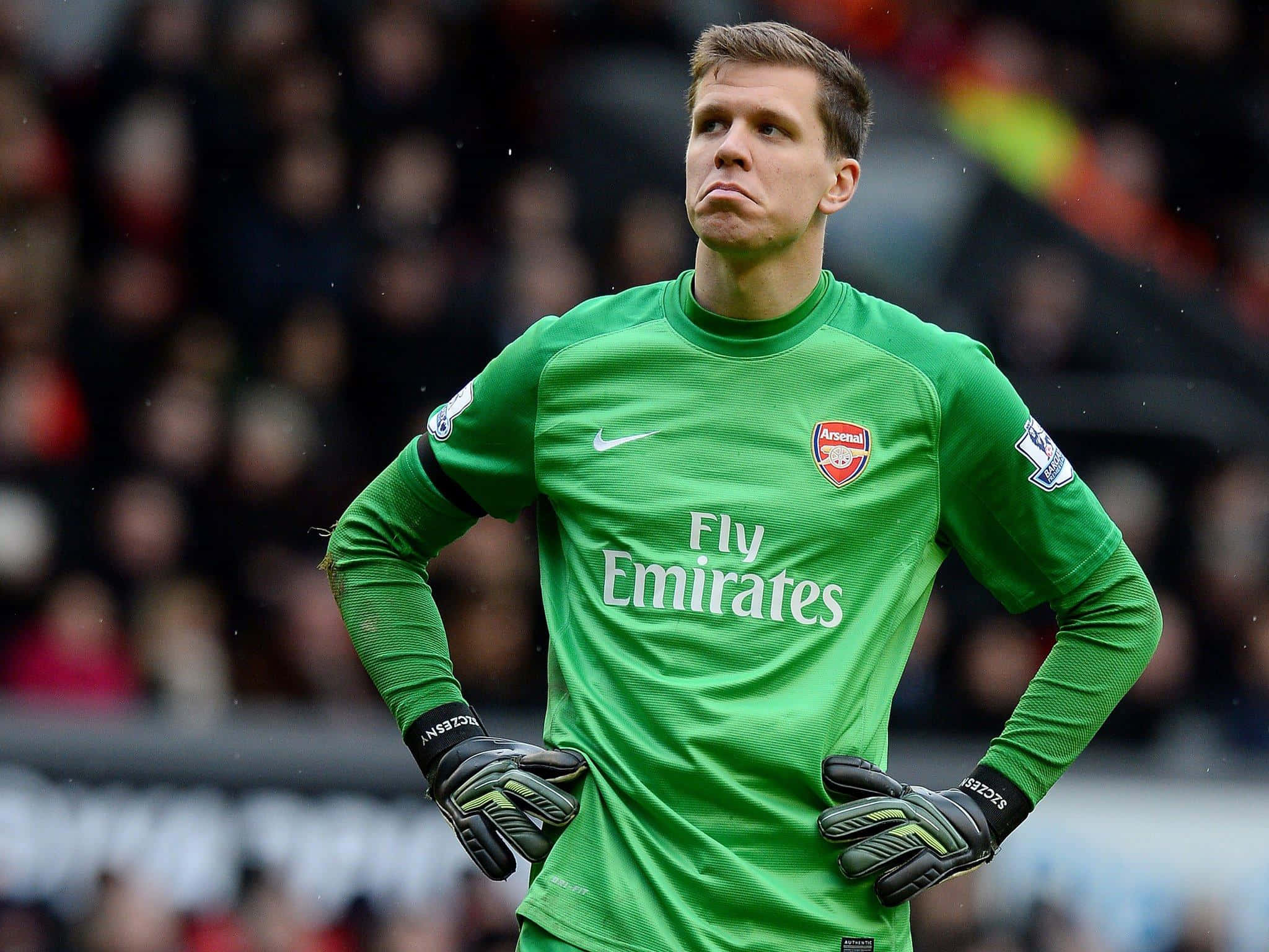 Wojciech Szczesny 桌布 壁紙 — 一位專注的足球守門員穿著亮綠色兵工廠球衣，在比賽中雙手叉腰站立。