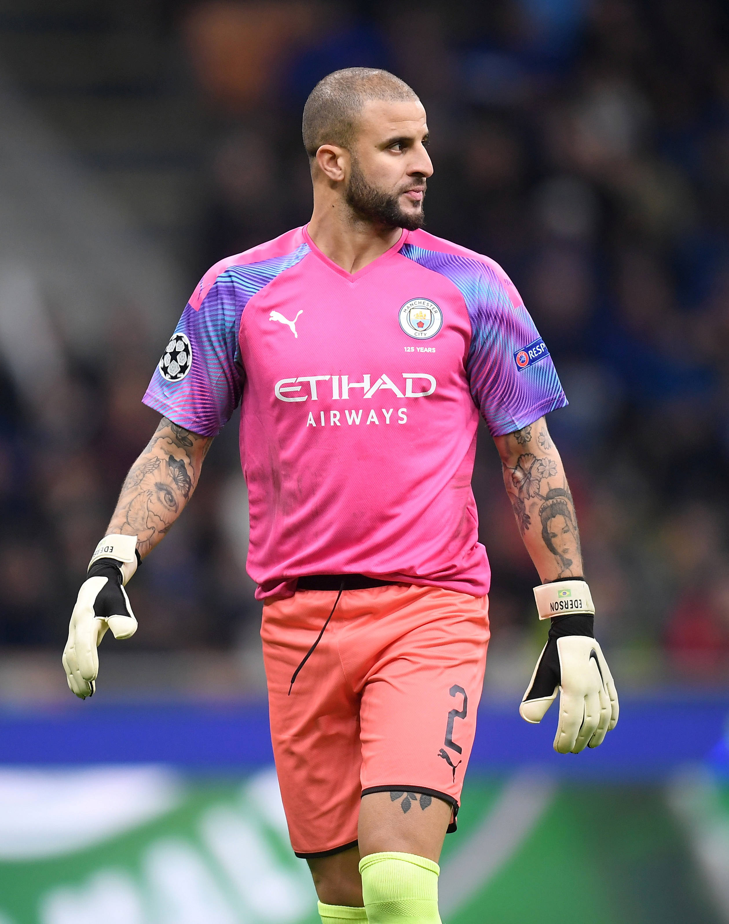 Kyle Walker 桌布 壁紙 — 一位專注的足球守門員身穿鮮豔的粉紅色和紫色球衣，站在球場上，手臂上的刺青清晰可見。