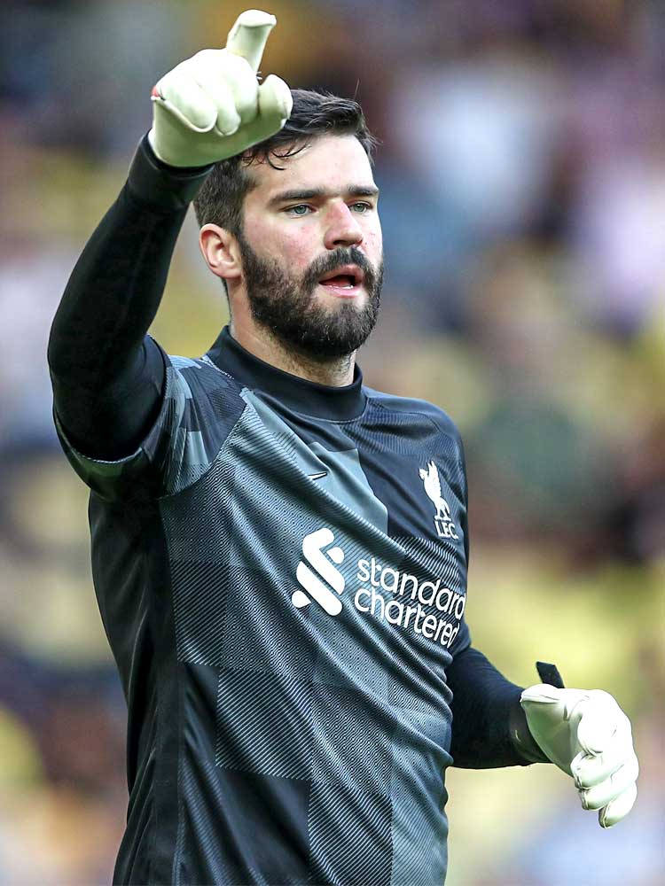 Alisson Becker 桌布 壁紙 — 一位專注的足球守門員身穿黑色利物浦球衣，在比賽中做出豎起大拇指的手勢。