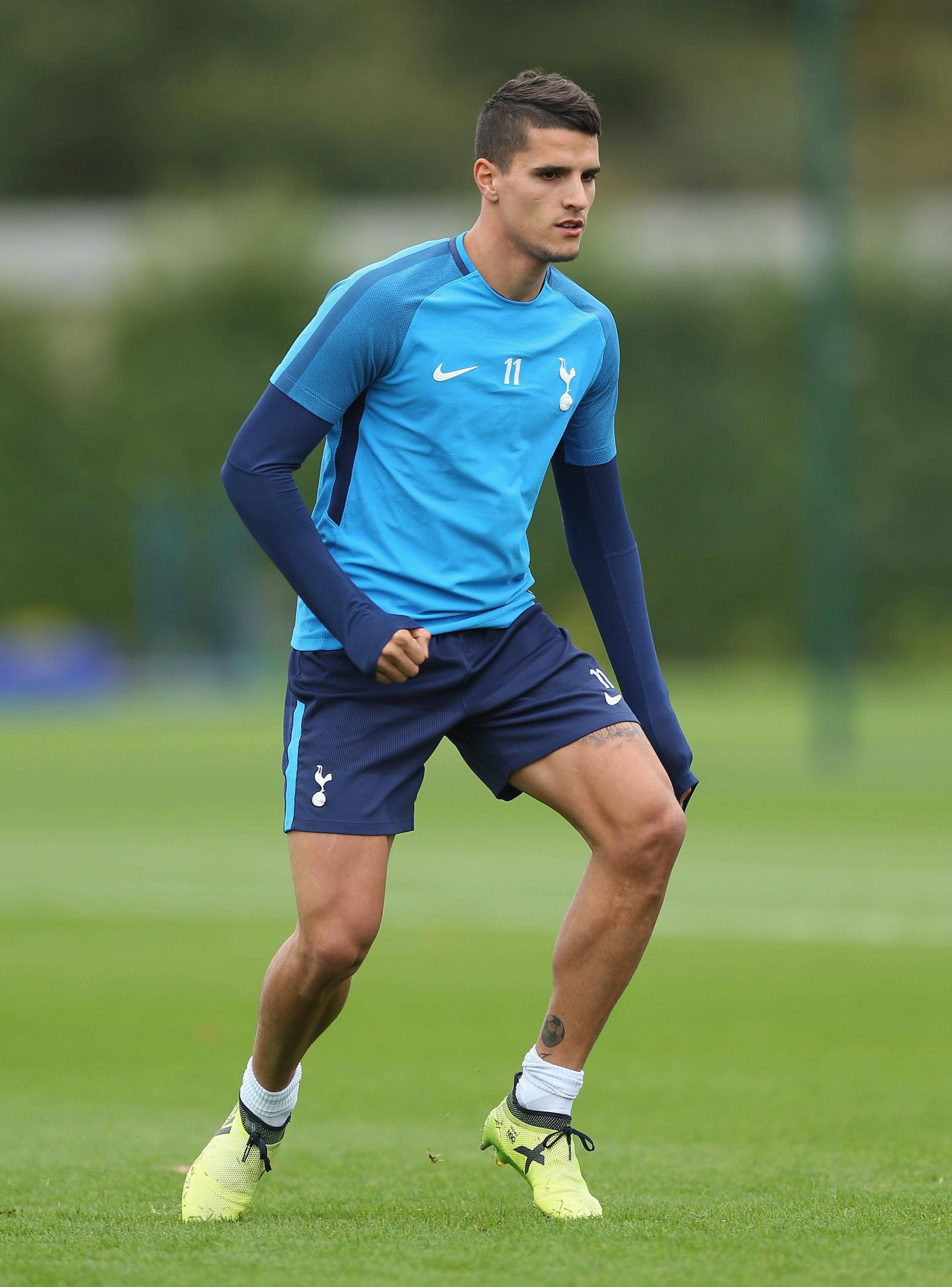 erik lamela 桌布 壁紙 — 一位專注的足球運動員穿著藍色訓練裝備，在練習期間站在茂密的綠色場地上。