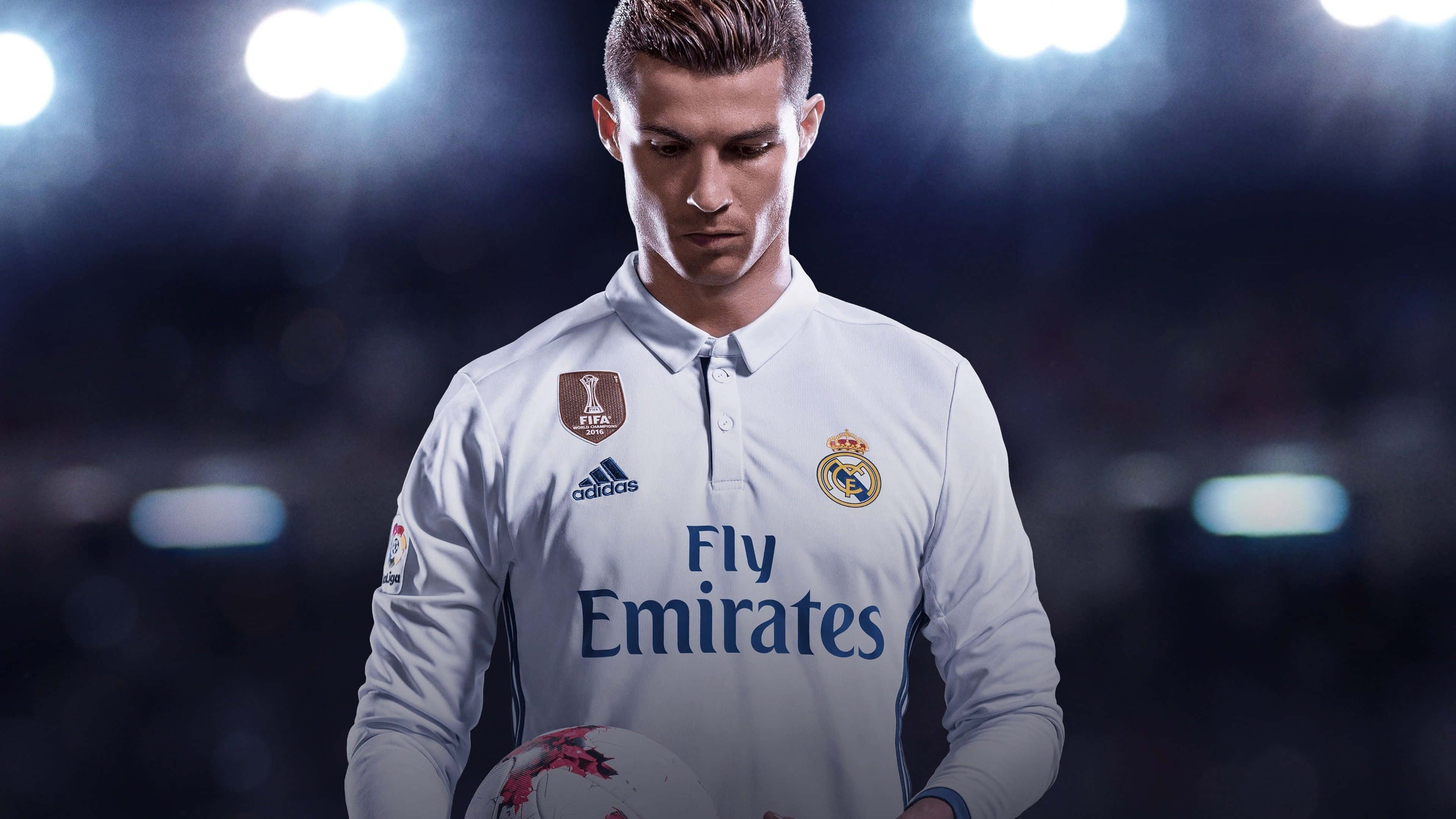 Cristiano Ronaldo 足球 桌布 壁紙 — 一位專注的足球運動員身穿白色皇家馬德里球衣，在明亮的體育場燈光下拿著球。