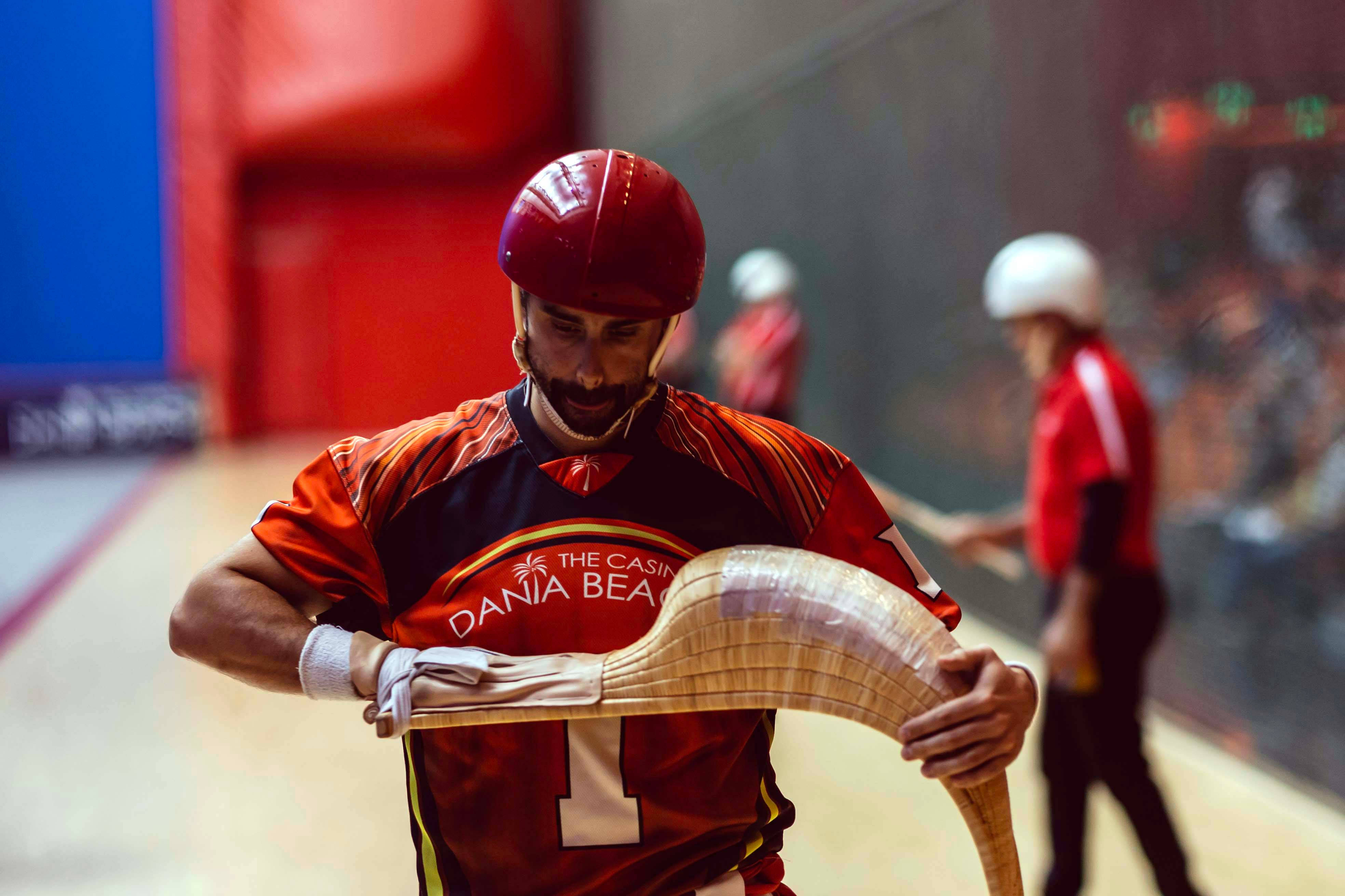 Athletic 桌布 壁紙 — 一位專注的迴力球選手身穿紅色裝備，在激烈的室內比賽中握著彎曲的塞斯塔。