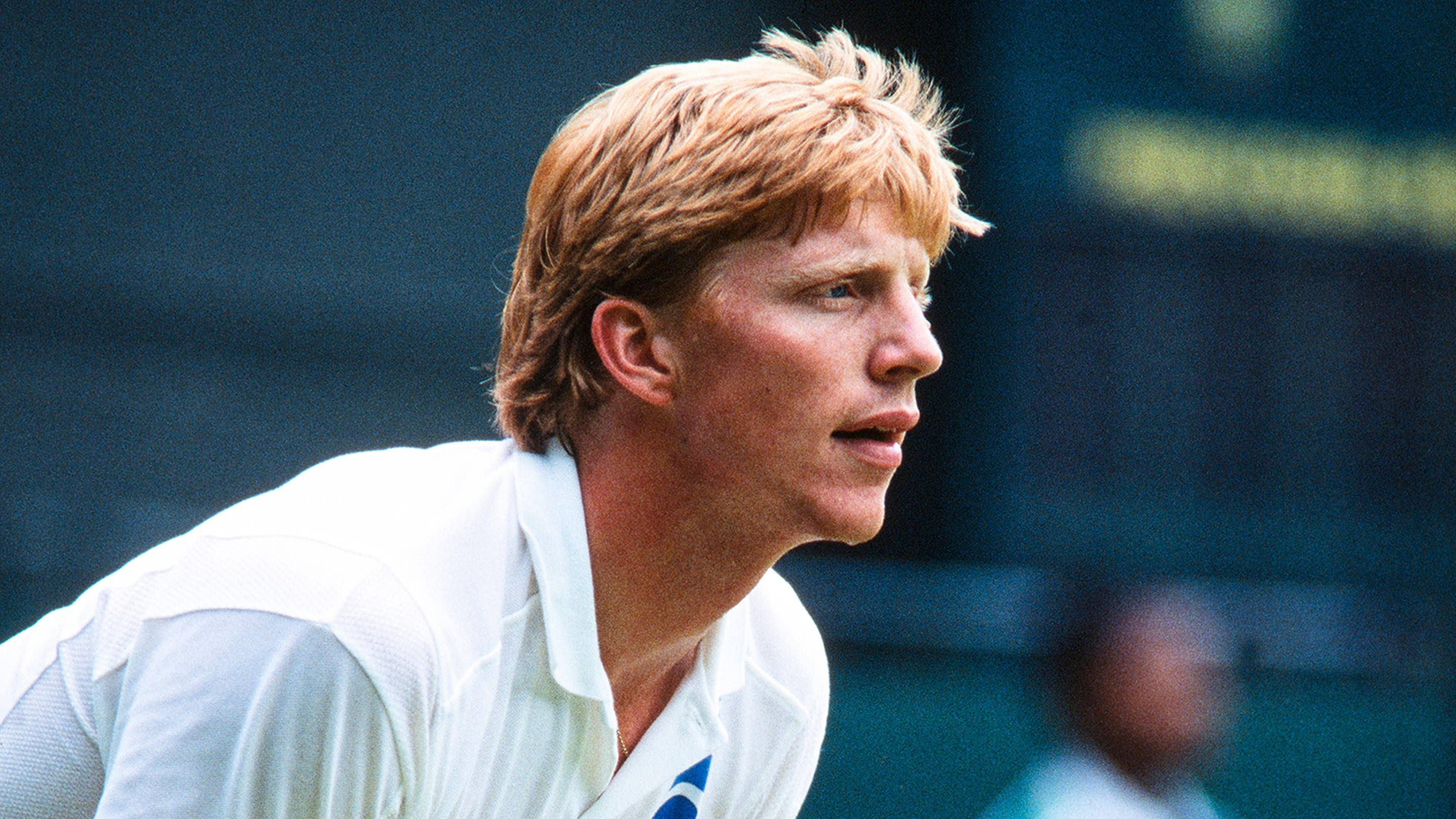 Boris Becker 桌布 壁紙 — 一位專注的金髮年輕網球運動員穿著白色襯衫，在明亮的日光下在球場上向前傾。