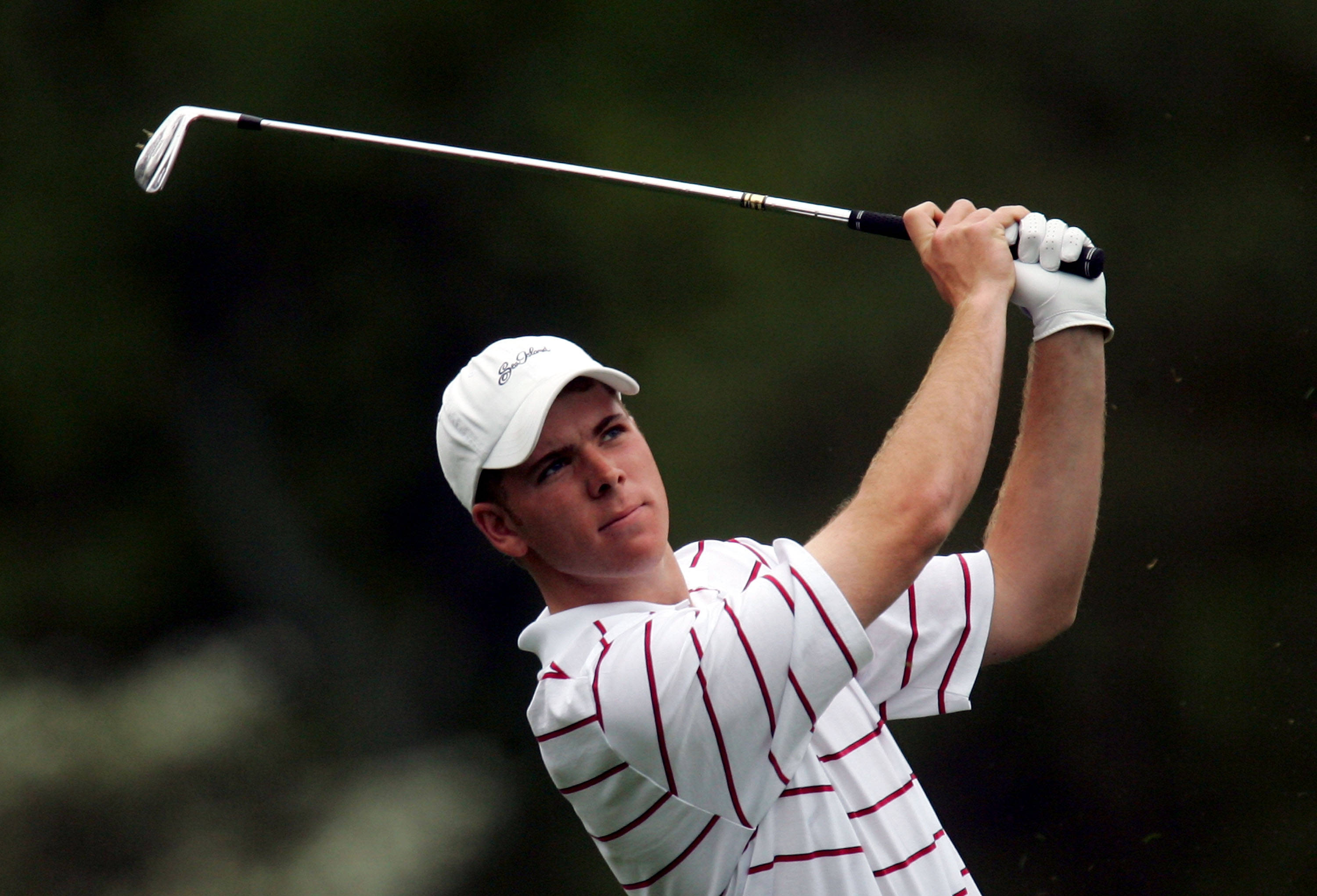 高爾夫 桌布 壁紙 — 一位專注的高爾夫球手在揮桿中，球桿高舉，背景是模糊的綠色。