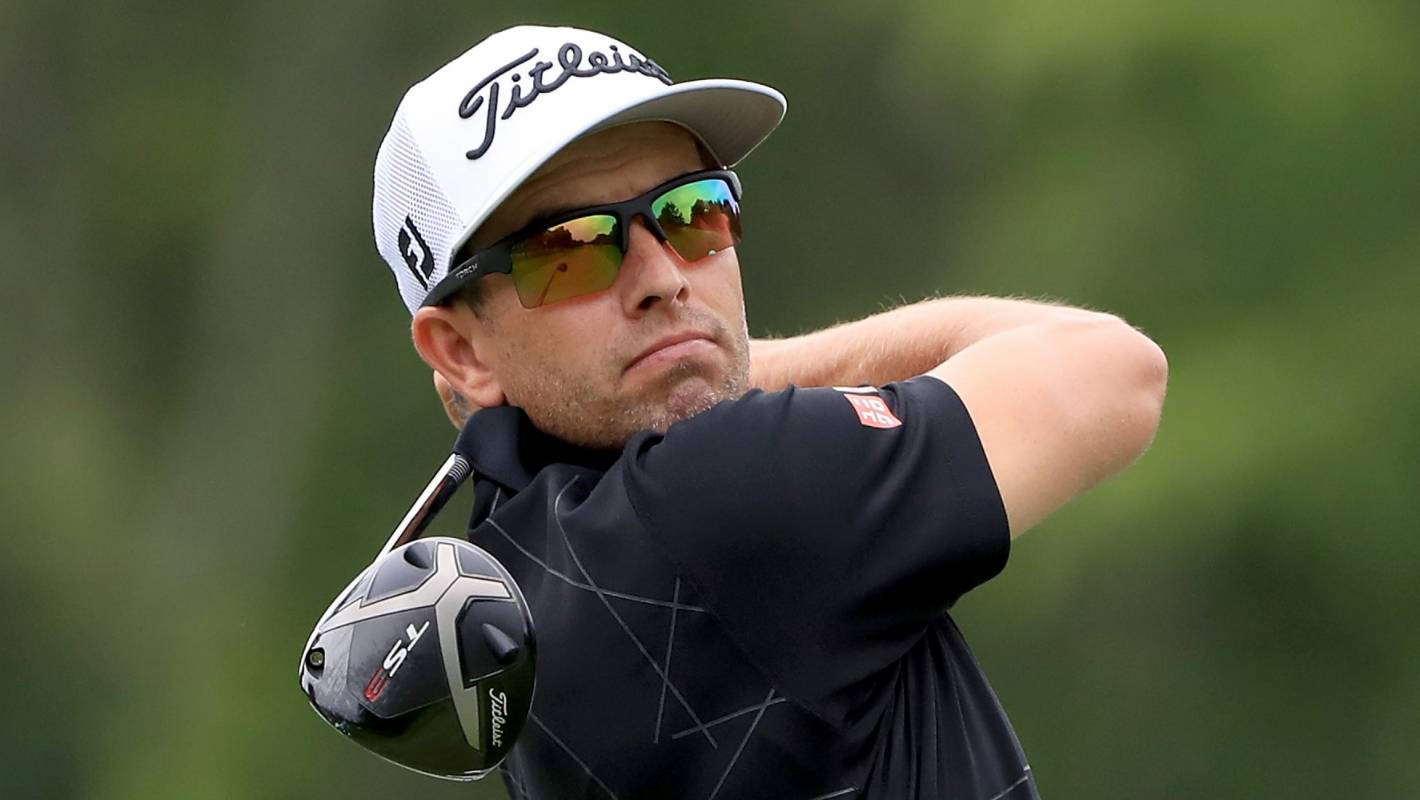 adam scott 桌布 壁紙 — 一位專注的高爾夫球手正在揮桿，戴著白色Titleist帽子和反光太陽眼鏡，背景是模糊的綠色。