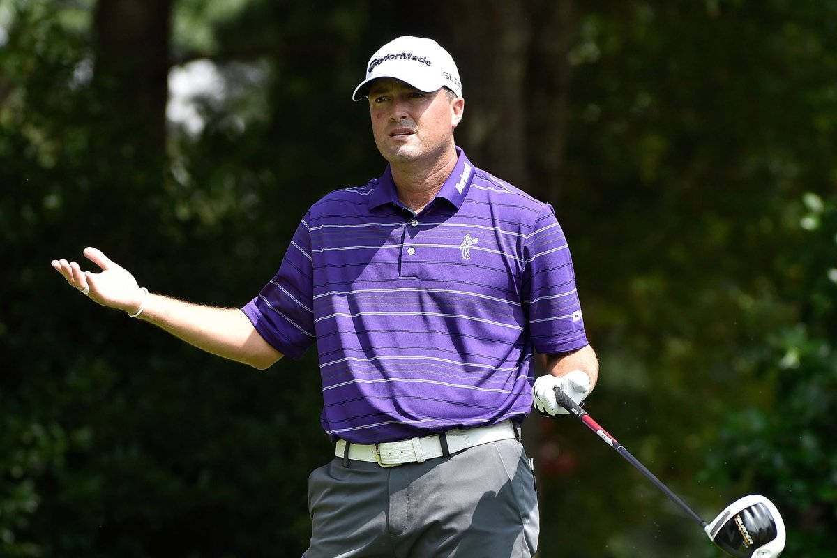 Ryan Palmer 桌布 壁紙 — 一位專注的高爾夫球手穿著紫色條紋襯衫，在茂密的綠色森林背景下揮桿中途做手勢。