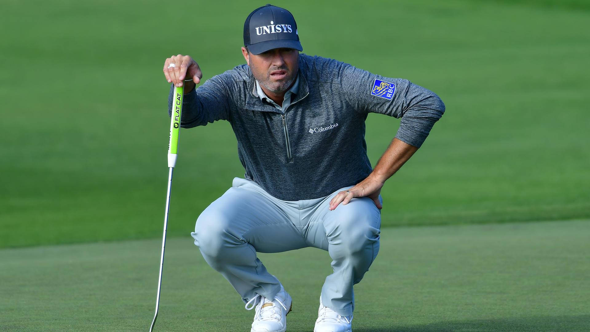 Ryan Palmer 桌布 壁紙 — 一位專注的高爾夫球手蹲在茂密的綠色球道上，手持亮綠色的推桿。