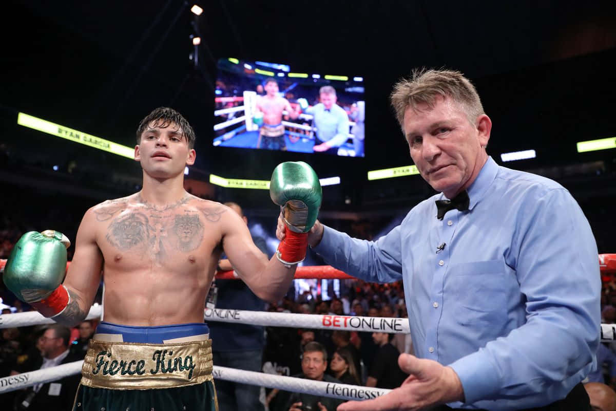 Ryan Garcia 桌布 壁紙 — 一位帶有刺青的勝利拳擊手站在擂台上，裁判在明亮的場館燈光和歡呼的人群中舉起他綠色的手套。