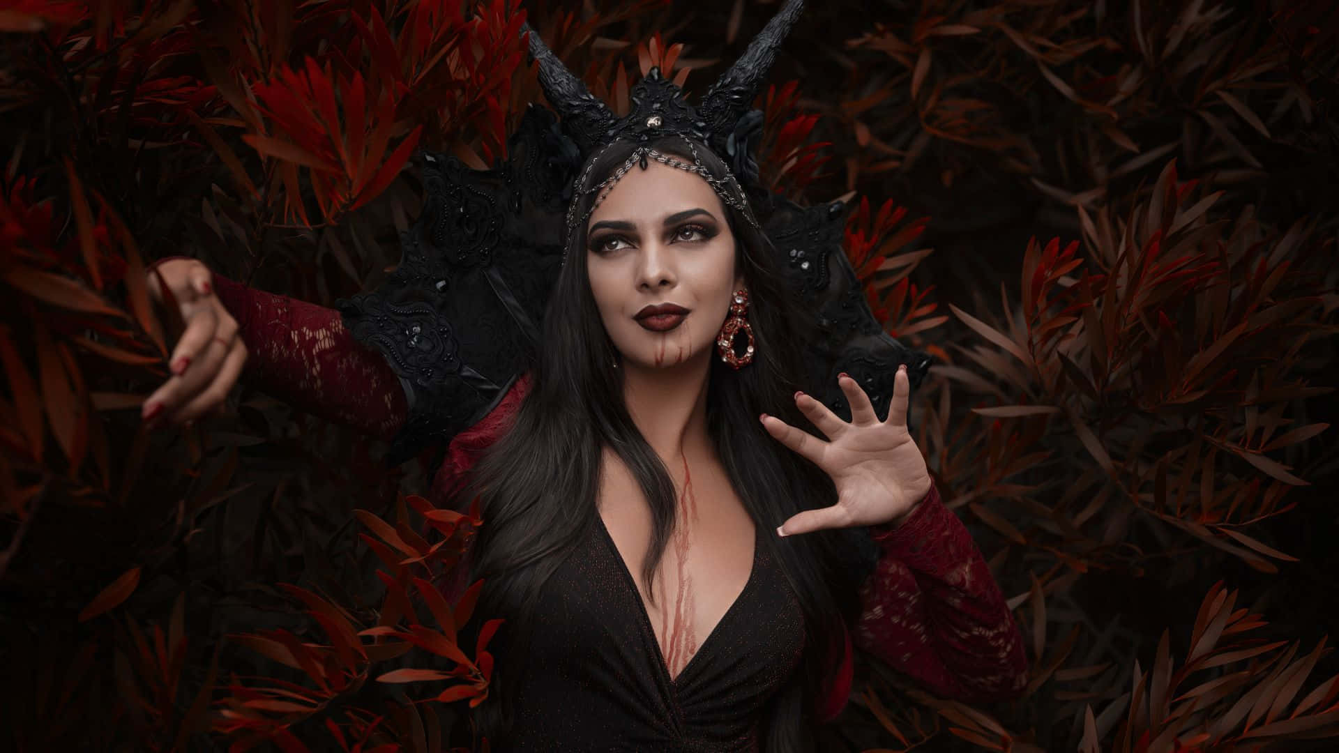 Horror Costumes 桌布 壁紙 — 一位帶有黑色角和紅色蕾絲袖子的暗黑魅力女性，從深紅色的樹葉中浮現，呈現出憂鬱的肖像。