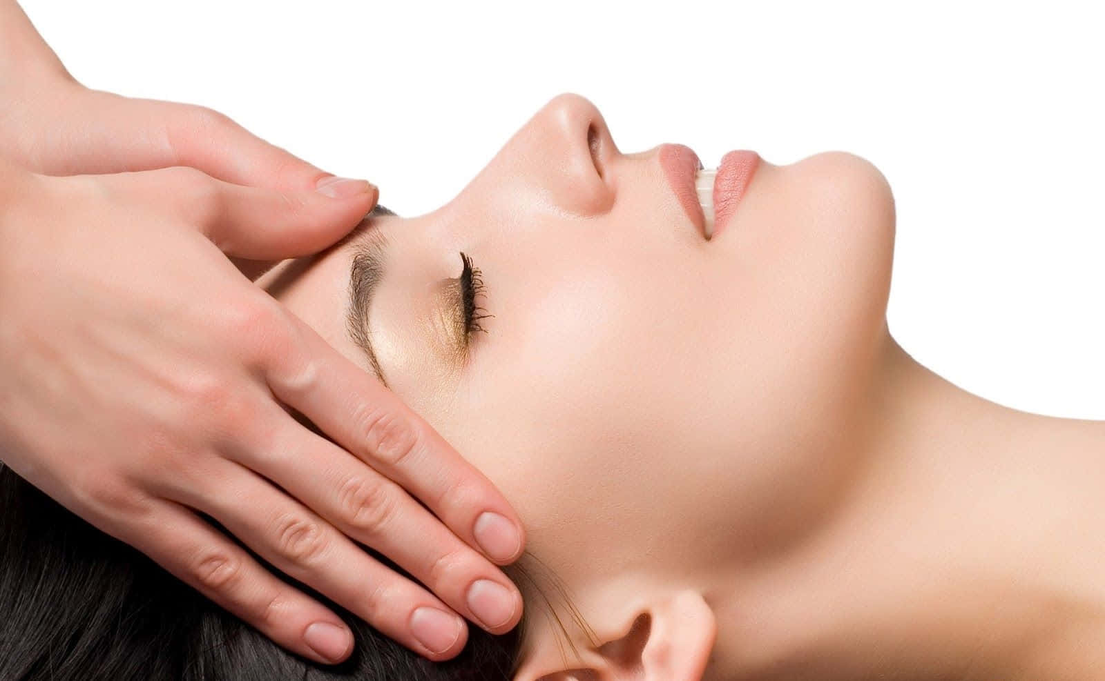 Massage 桌布 壁紙 — 一位平靜的女性閉上眼睛，在純白背景下接受輕柔的臉部按摩。
