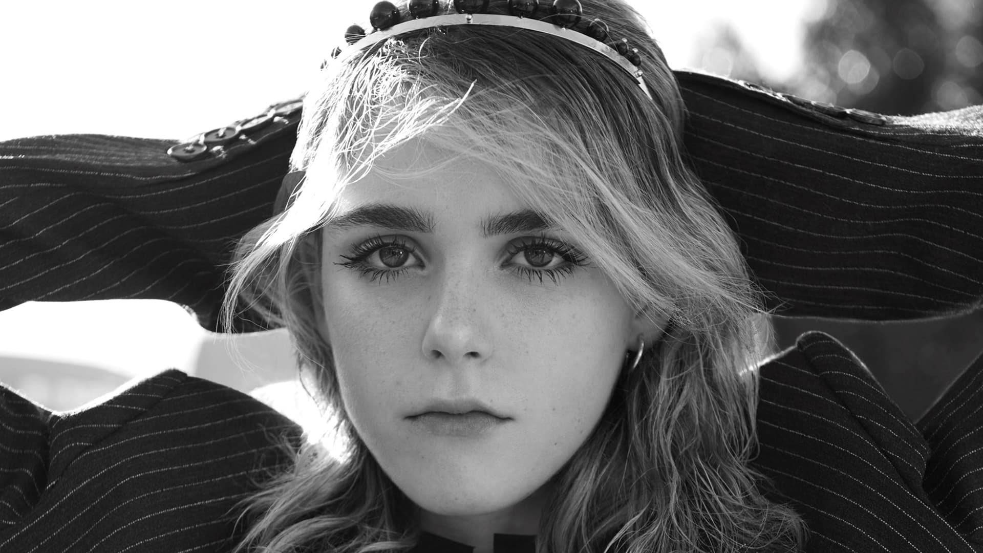 Kiernan Shipka 桌布 壁紙 — 一位年輕女子，臉上帶有雀斑，頭戴髮帶，以嚴肅的表情直視鏡頭的黑白肖像。