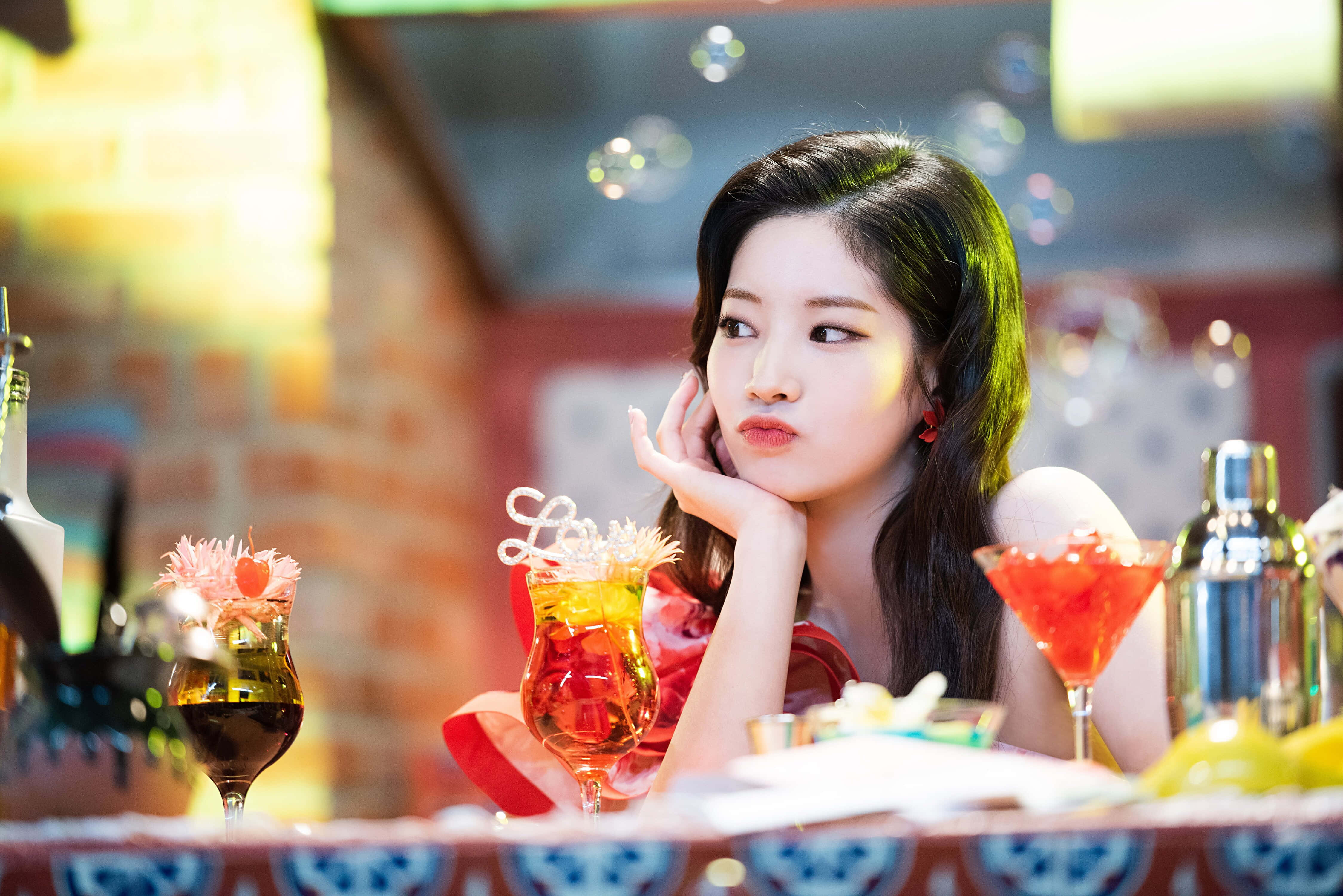 twice 桌布 壁紙 — 一位年輕女子在充滿活力的酒吧裡，用手托著下巴，周圍是色彩繽紛的雞尾酒和漂浮的氣泡。