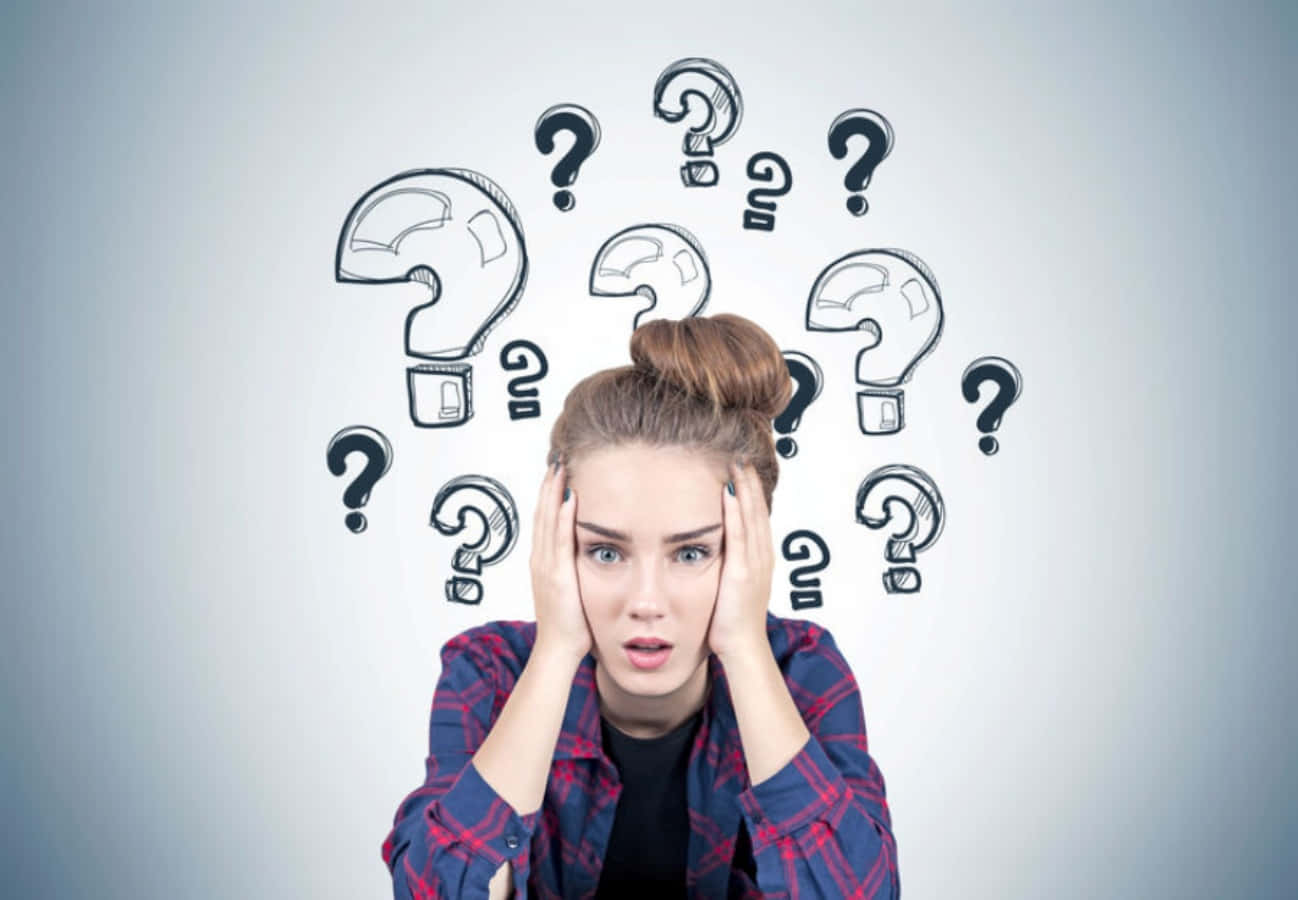 Confused 桌布 壁紙 — 一位年輕女子雙手放在頭上，看起來被周圍漂浮的手繪問號淹沒了。