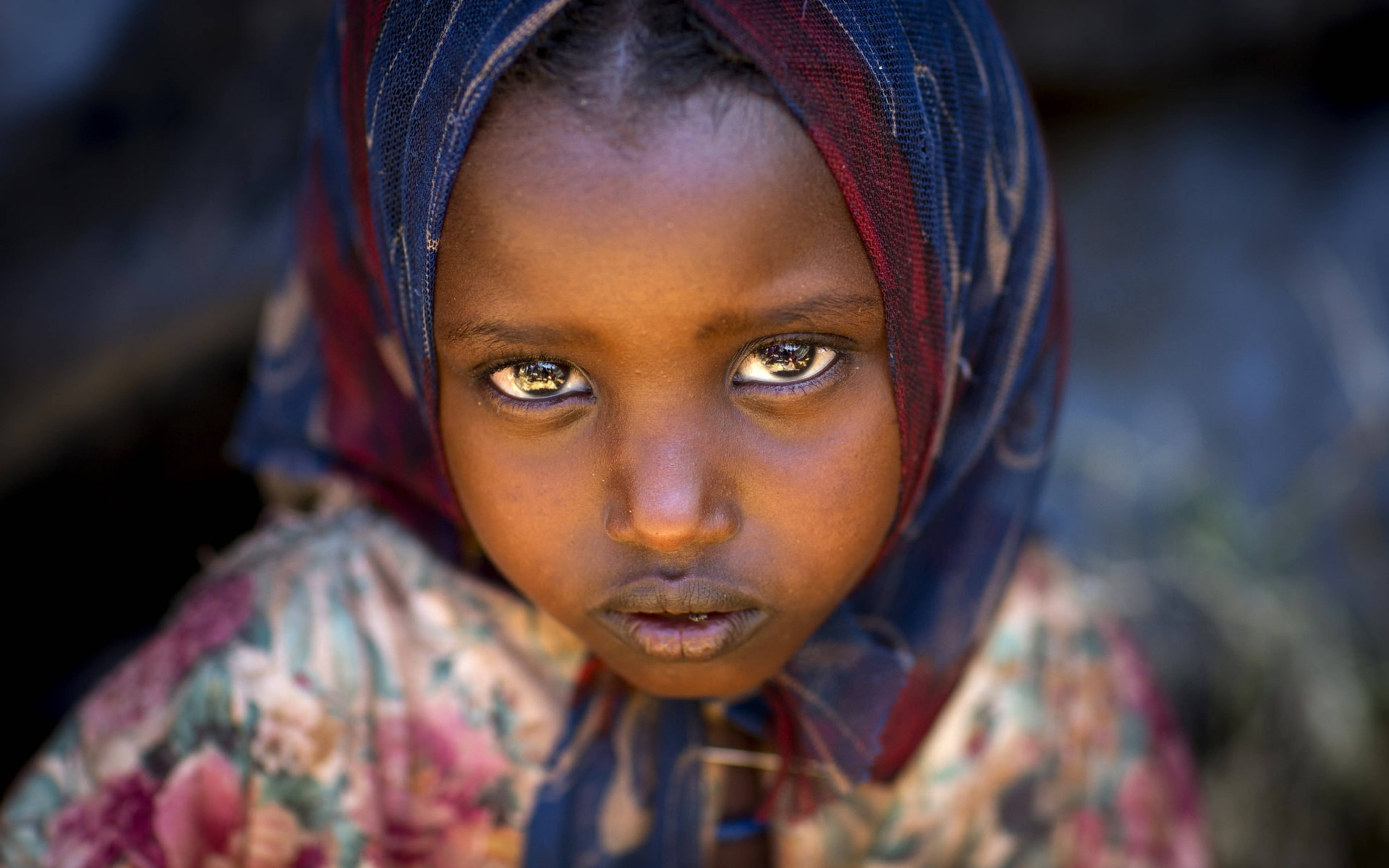 Ethiopia 桌布 壁紙 — 一位年輕女孩的特寫肖像，她有著引人注目的眼睛和圖案頭巾，直視鏡頭。