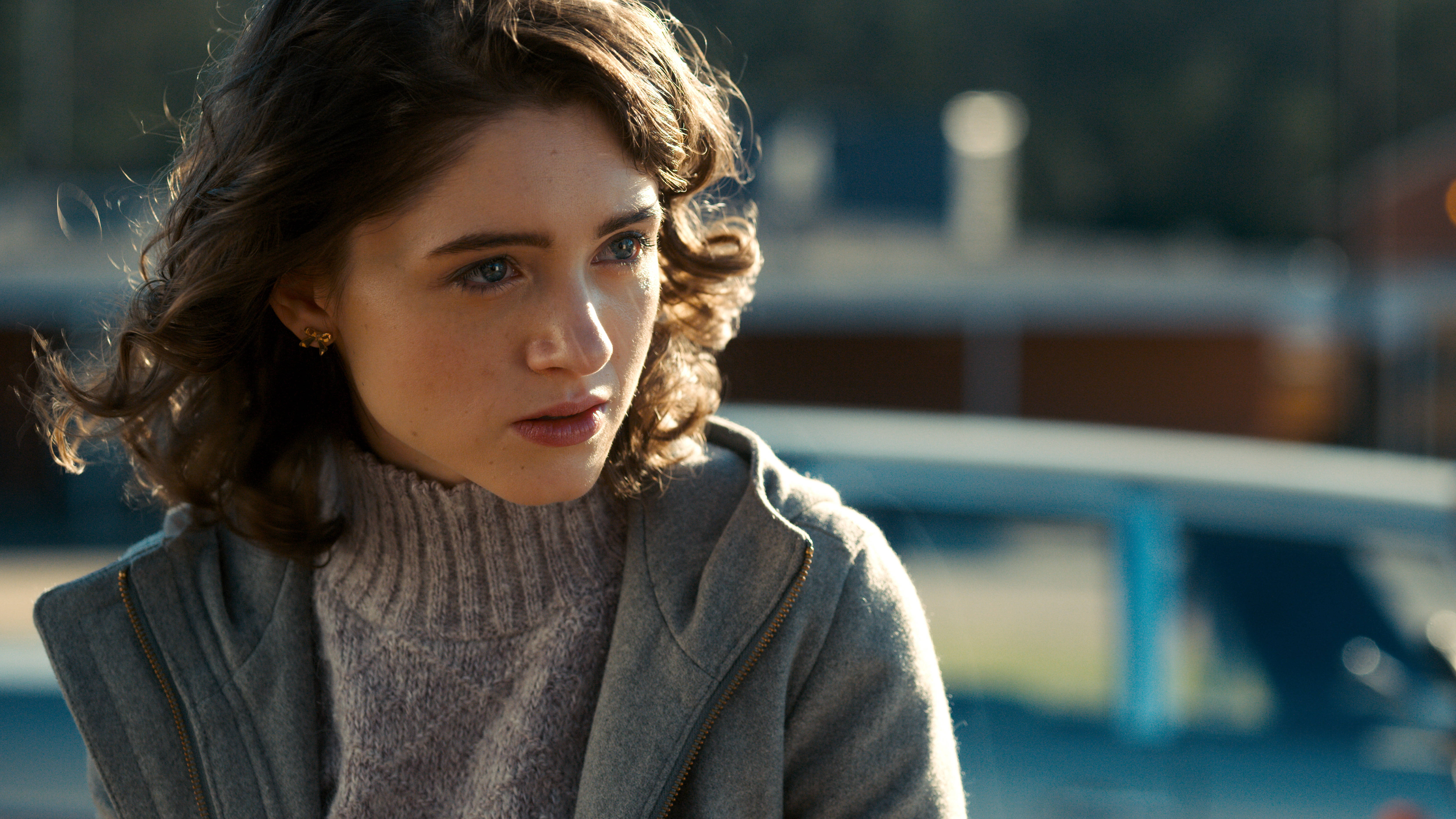 Netflix 桌布 壁紙 — 一位年輕女性，一頭棕色捲髮，在柔和的金色陽光下若有所思地凝視戶外。
