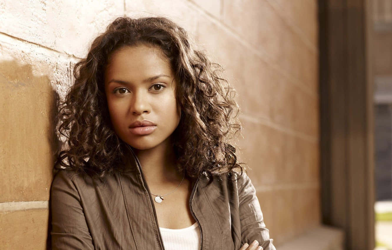 Gugu Mbatha-raw 桌布 壁紙 — 一位年輕女性，一頭棕色捲髮，靠著紋理石牆，直視前方，表情嚴肅。