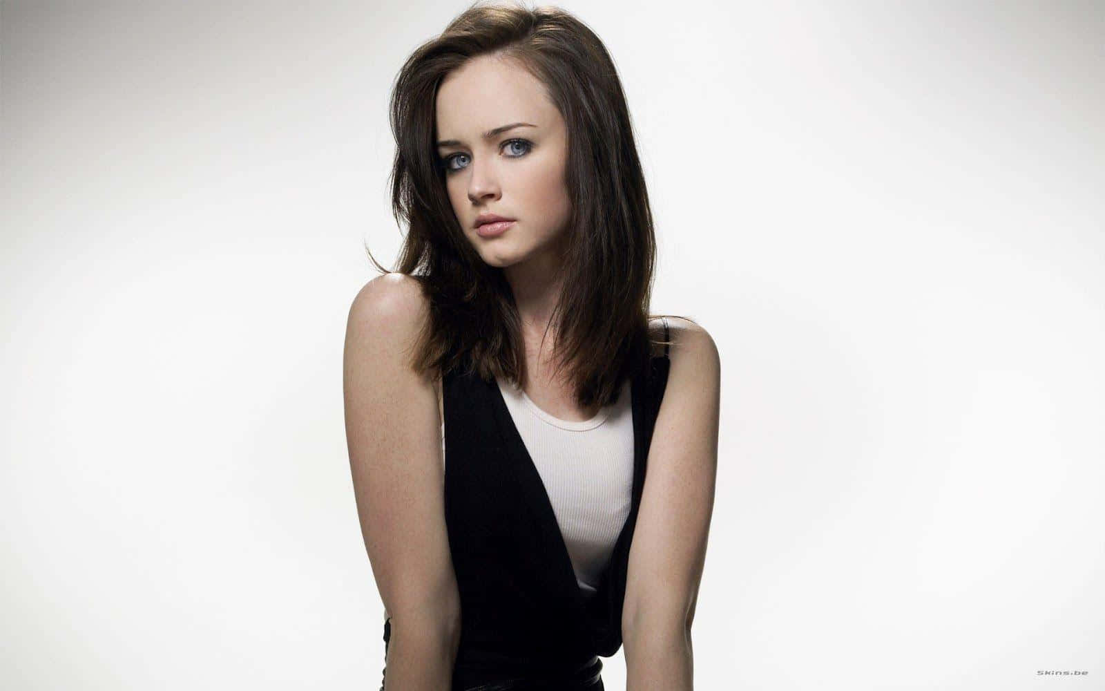 Alexis Bledel 桌布 壁紙 — 一位年輕女性，擁有引人注目的藍色眼睛和棕色頭髮，在純白背景前若有所思地凝視。