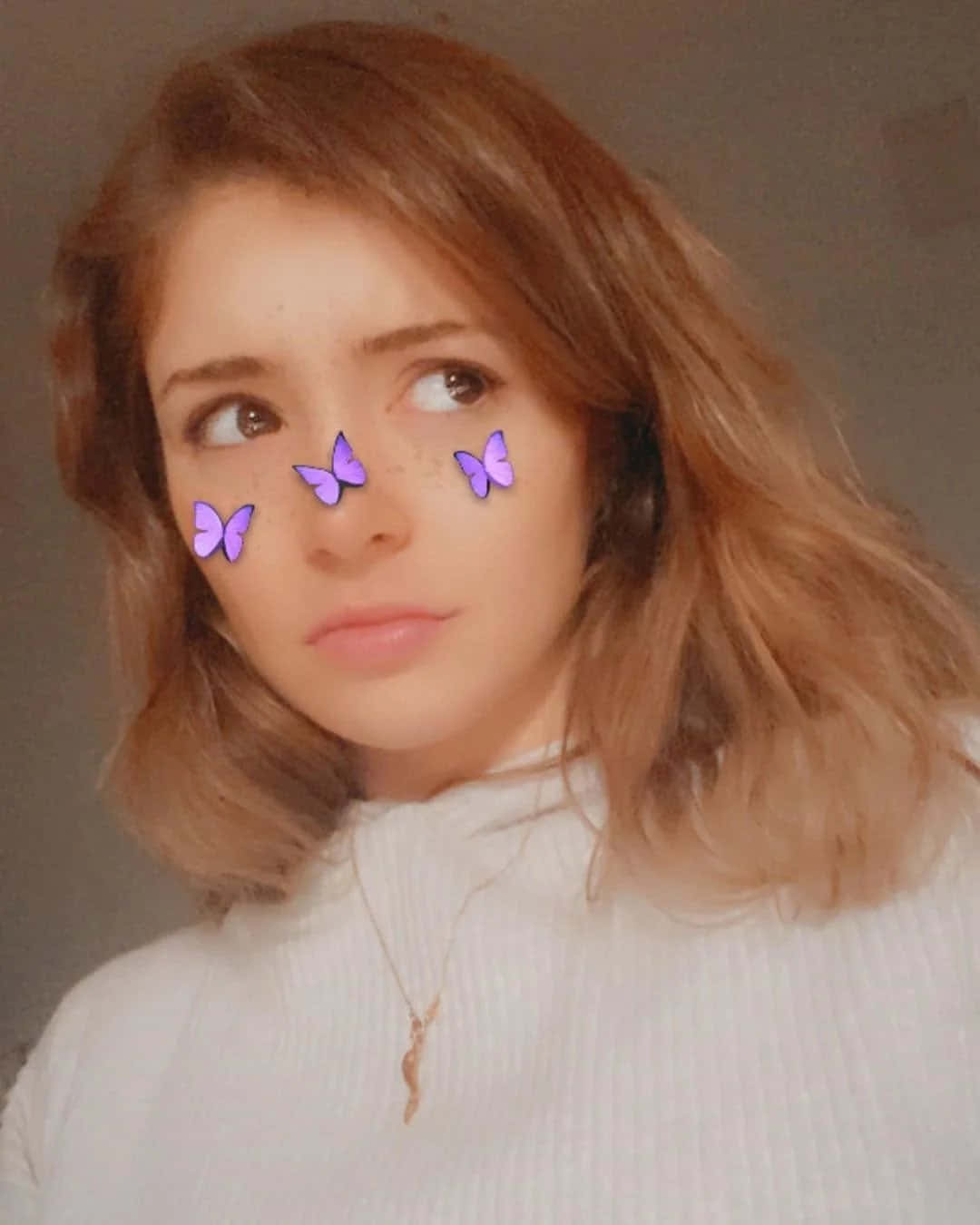 Snapchat 桌布 壁紙 — 一位年輕女性，擁有波浪形棕色頭髮，眼睛附近數位放置了紫色蝴蝶，穿著白色羅紋高領毛衣，側視。