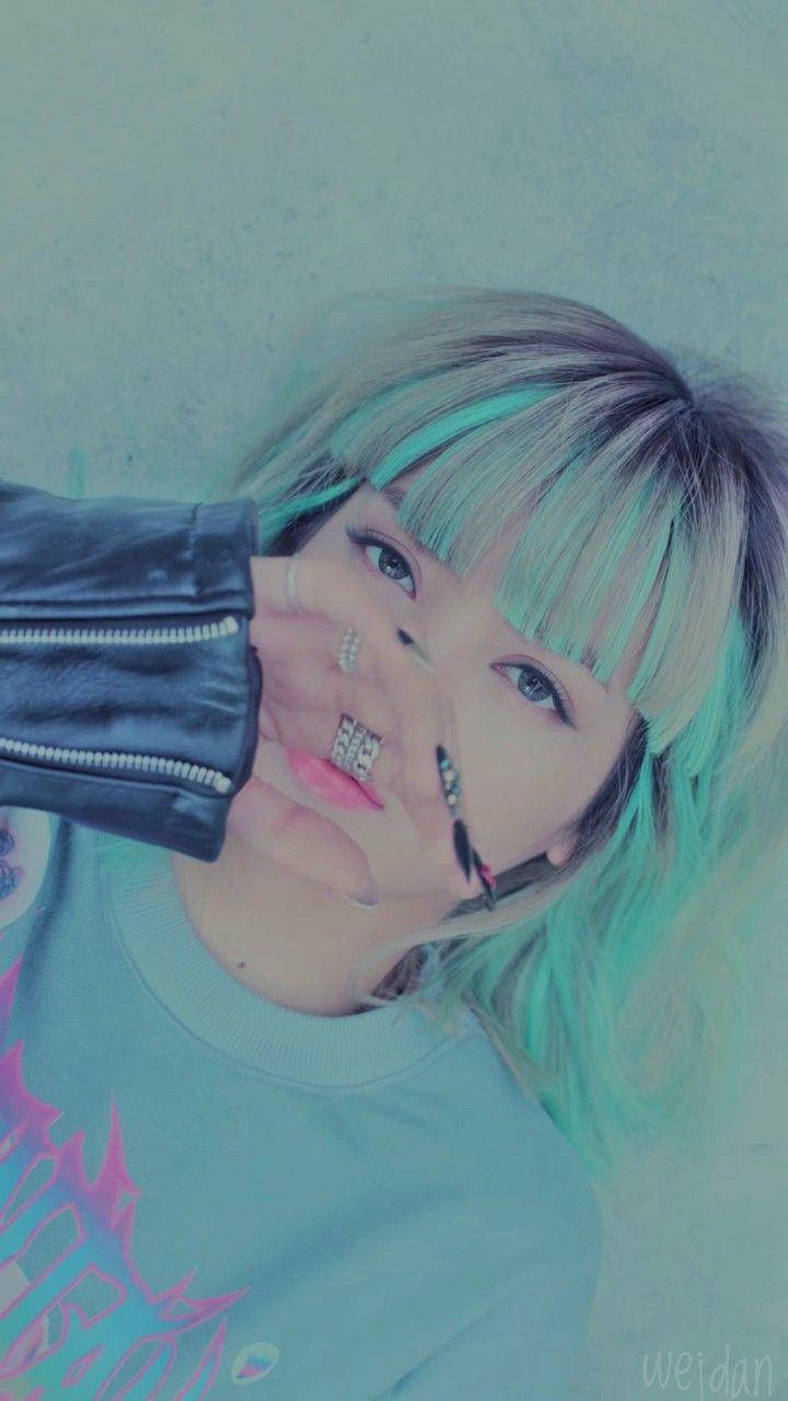 年輕女性，青綠色頭髮和戒指，舉起黑色夾克袖子。 — BLACKPINK Lisa GIF 壁紙