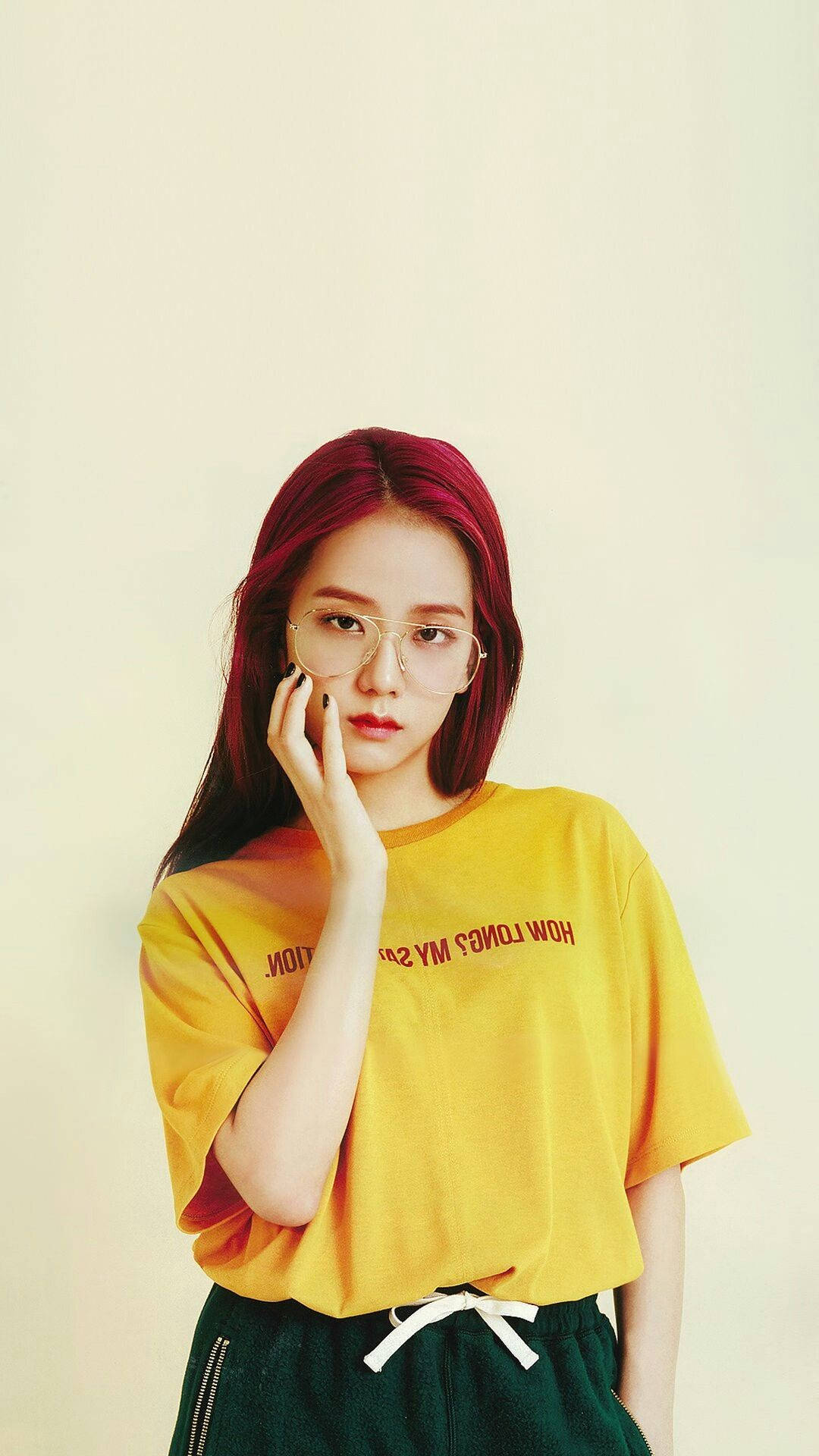 BLACKPINK 桌布 壁紙 — 一位年輕女性，擁有鮮豔的紅髮和眼鏡，穿著黃色T恤，在純米色背景前若有所思地擺姿勢。