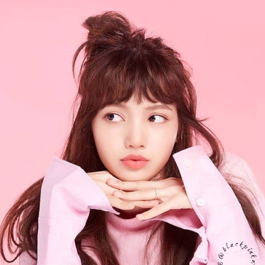 BLACKPINK 桌布 壁紙 — 一位年輕女性，棕色頭髮紮成凌亂的髮髻，雙手托腮，背景為純粉色。