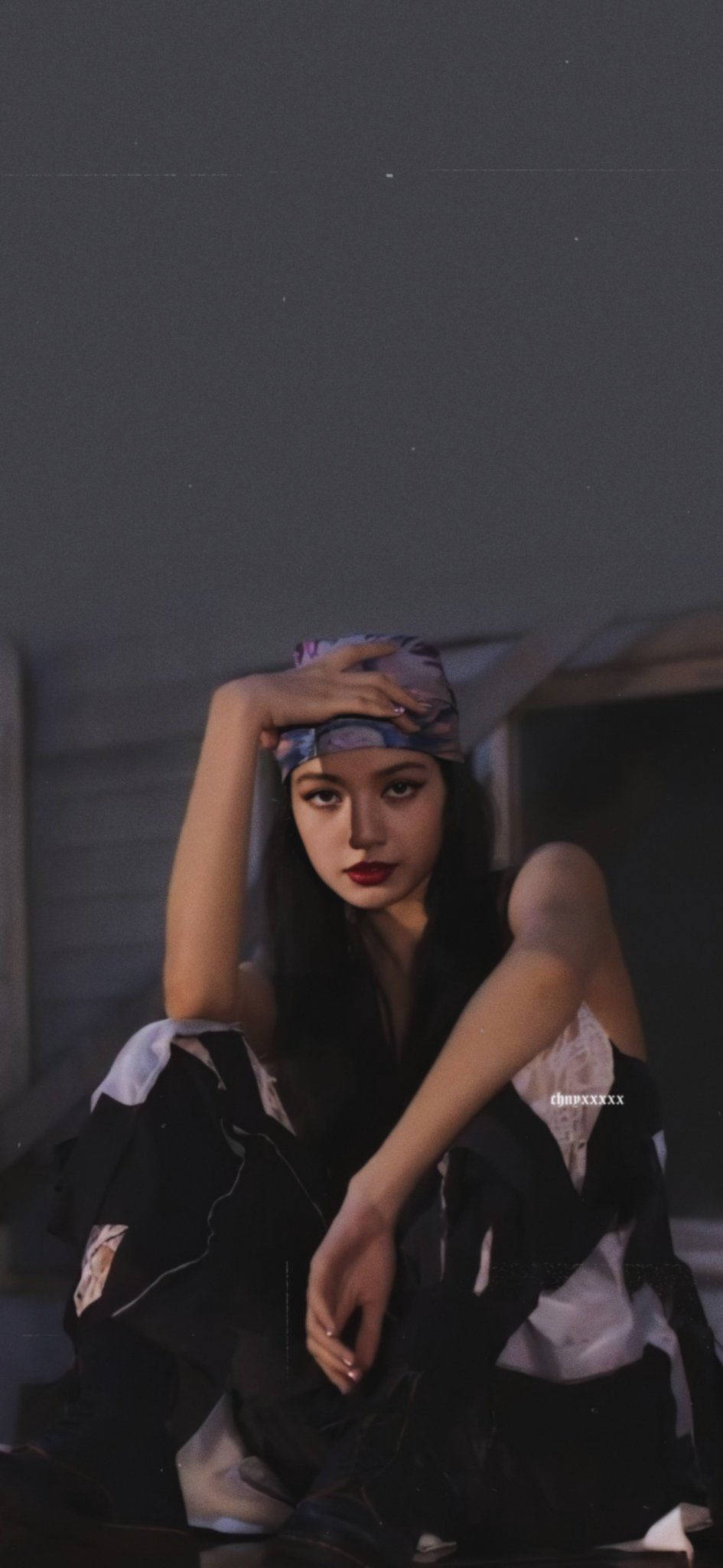 Lalisa 桌布 壁紙 — 一位年輕女性，深色頭髮，大膽紅唇，坐在昏暗的房間裡，戴著圖案頭巾，穿著黑白服裝，手放在額頭上。