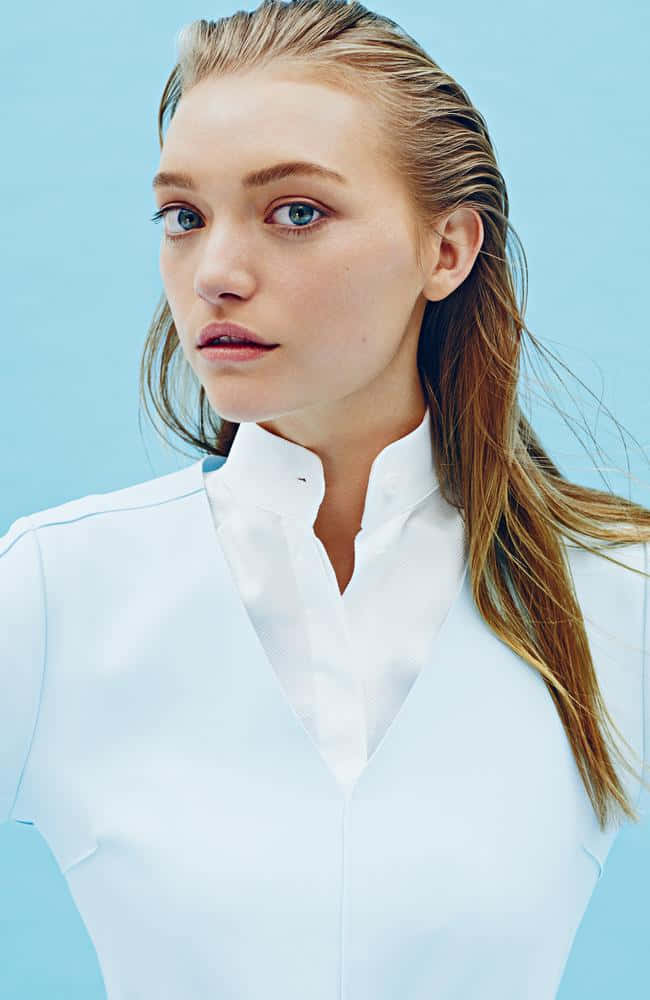 Gemma Ward 桌布 壁紙 — 一位年輕女性，濕透的金色頭髮和藍色眼睛，穿著潔白襯衫，在純淺藍色背景前直視鏡頭。