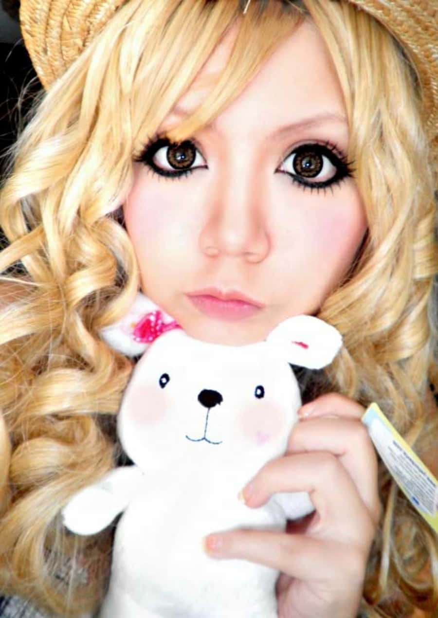 Gyaru 桌布 壁紙 — 一位年輕女性，金色捲髮，妝容誇張，在深色背景前抱著一隻白色毛絨兔子。