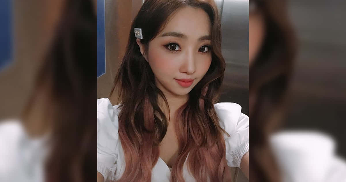 2NE1 桌布 壁紙 — 一位年輕女性，長長的波浪棕色頭髮，白色襯衫，化著淡妝，戴著銀色髮夾，看著鏡頭。